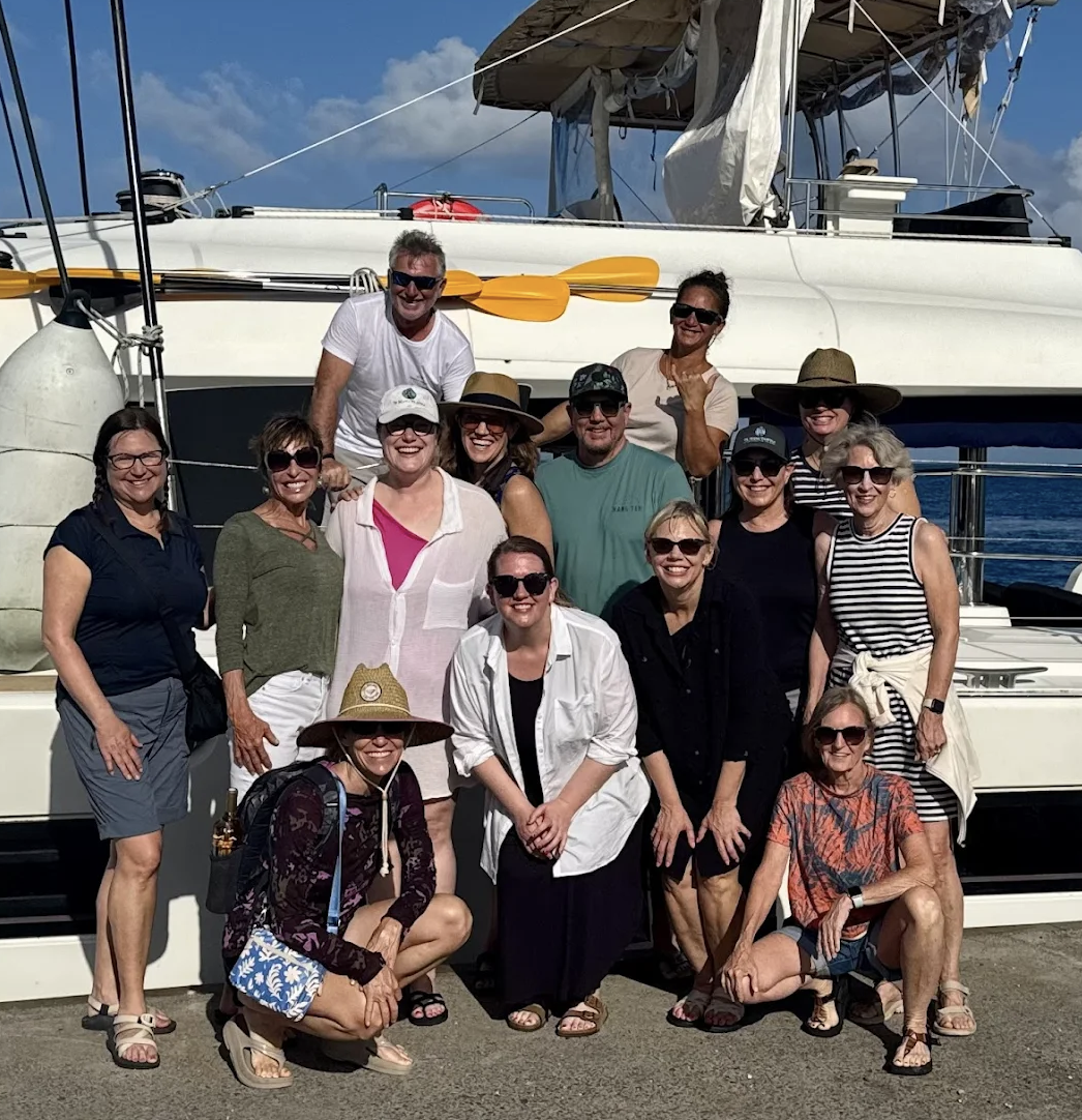 Smiling crew standing in front of catamaran after sailing in Tahiti with Te Mana Travels.