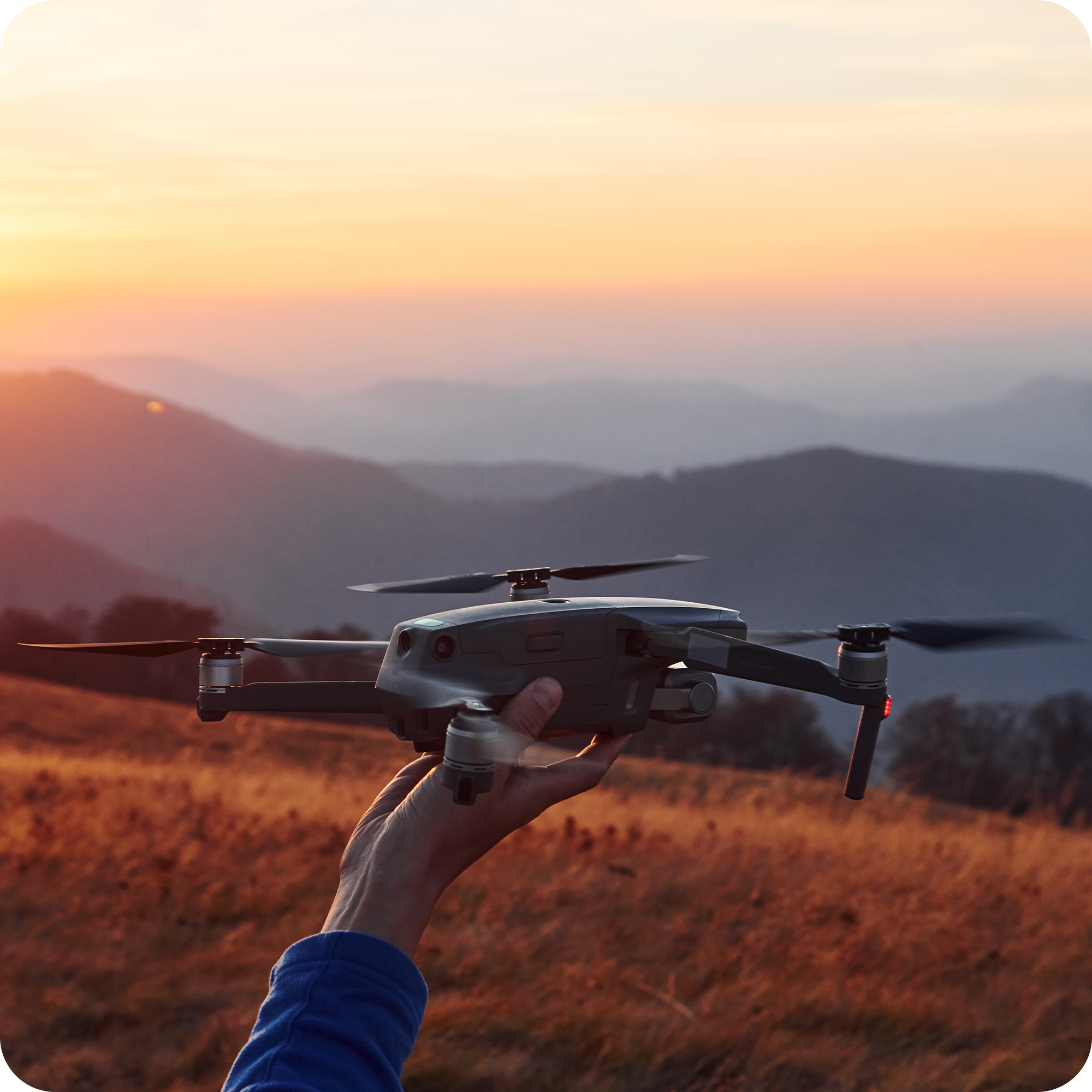 Aspiring drone pilot launching a compact quadcopter at golden hour in the mountains – hands-on flight training in a professional Drone Academy setting, mastering aerial photography and safe flight skills.