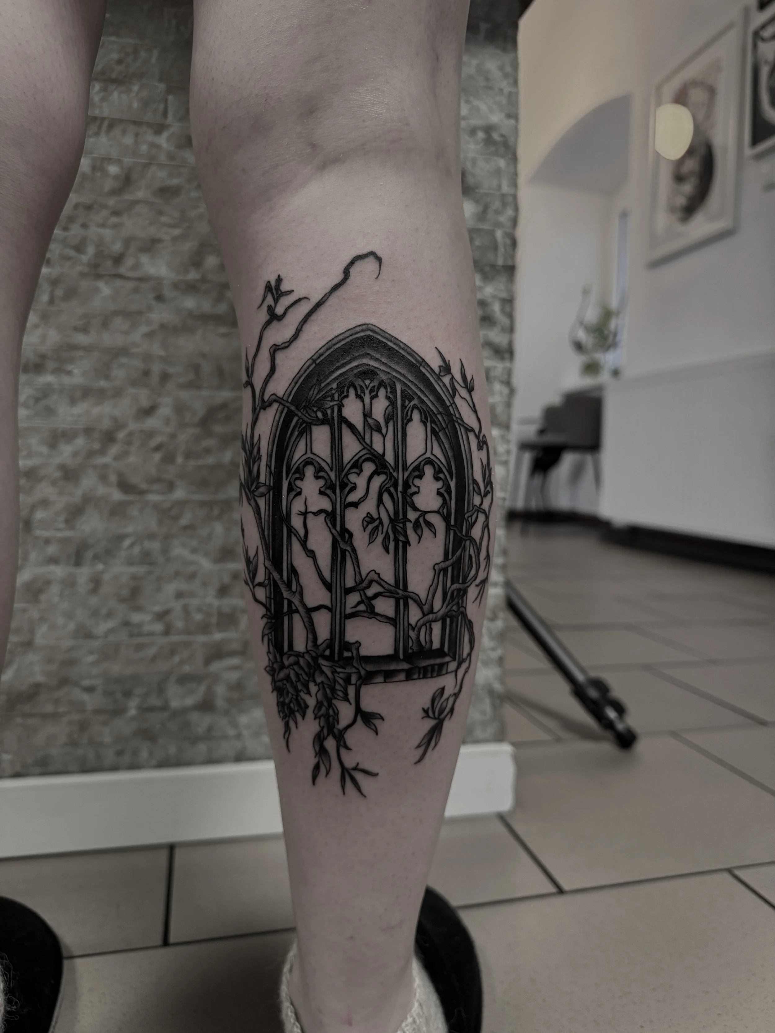 Hinter einem Gitterfenster wachsen Fliesen und Zweige.