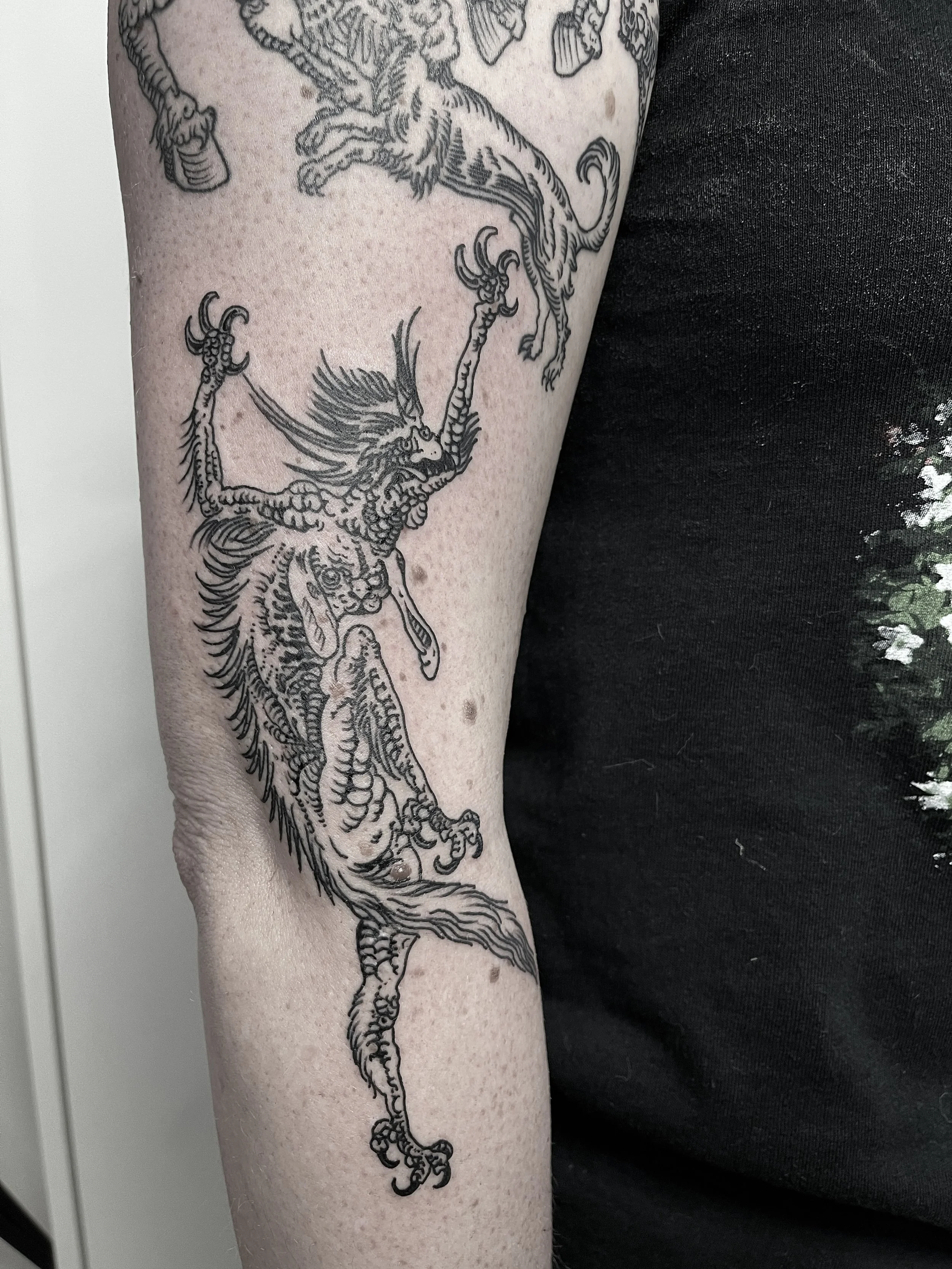 Tattoo eines kämpfenden chinesischen Drachen auf dem Oberarm einer Person