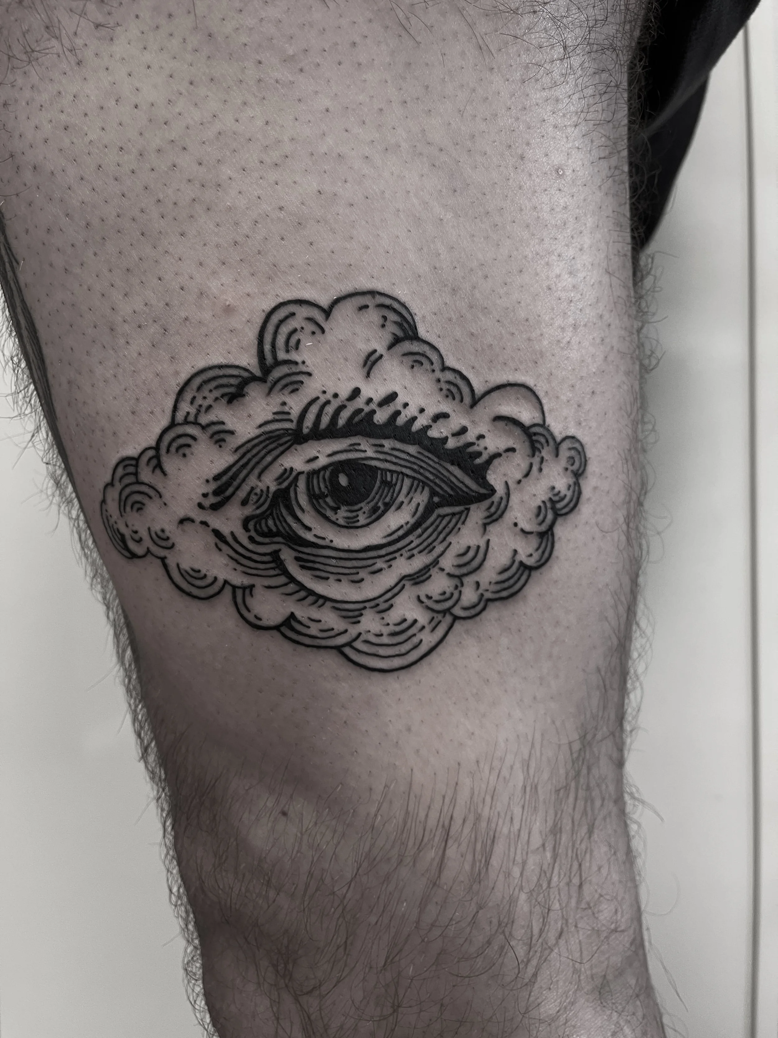 Tattoo eines Auges in einer Wolke auf einem Oberschenkel