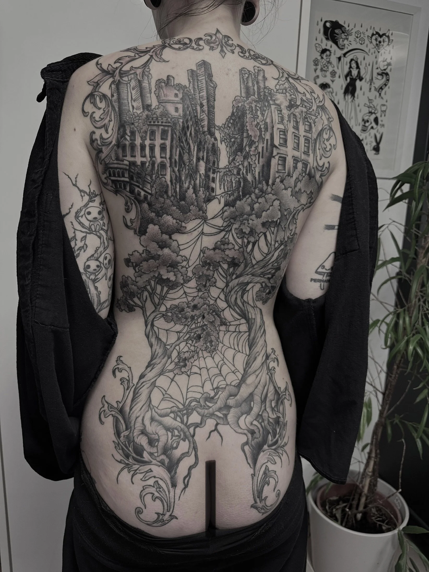 Tattoo eines Baumes mit verworrenen Wurzeln und einem Stadtbild auf dem Rücken.