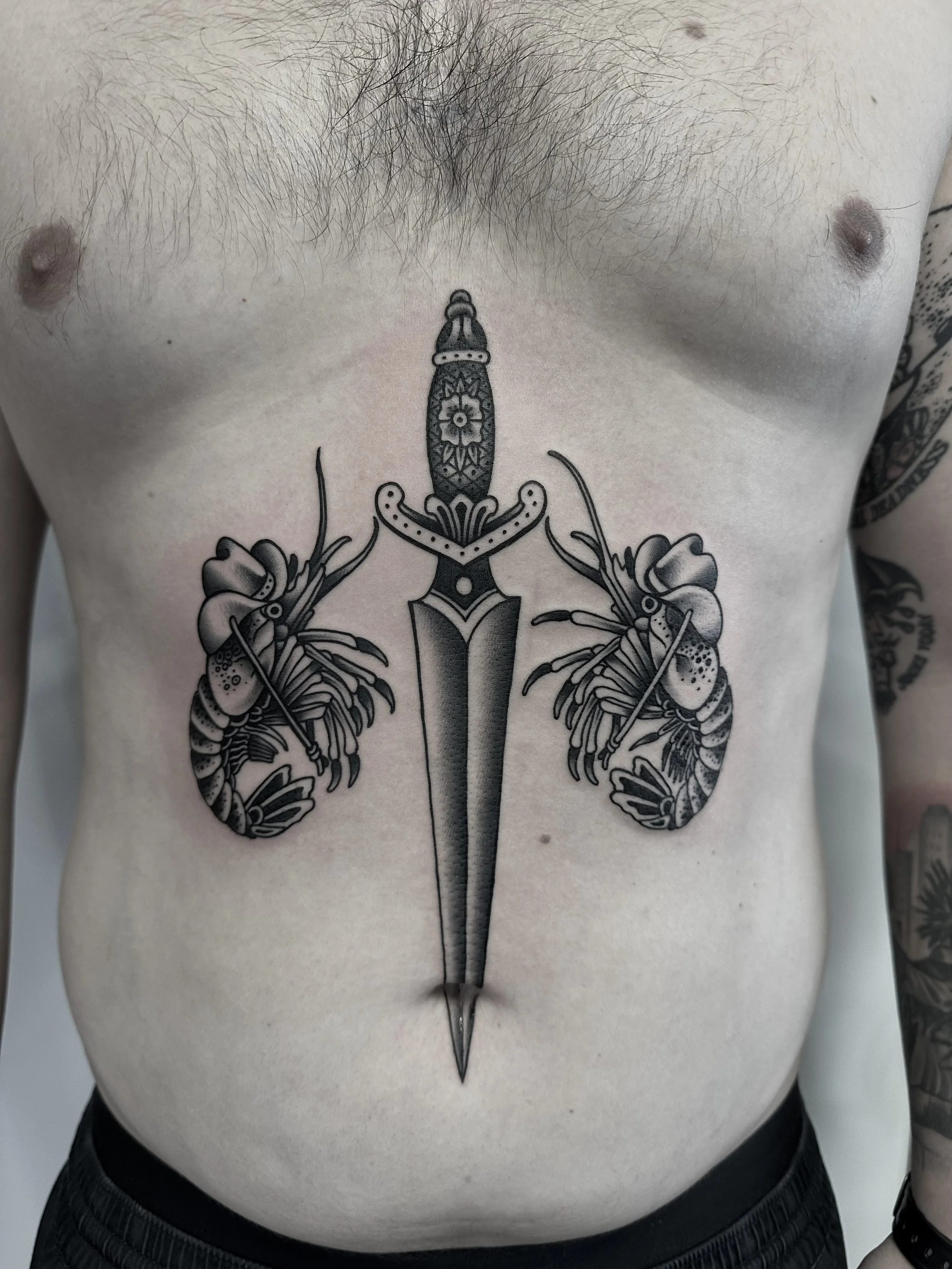 Tattoo auf der Brust eines Mannes, das ein Messer mit Flammenmuster in der Mitte und zwei Muscheln auf jeder Seite zeigt, mit Nähnadeln in den Muscheln