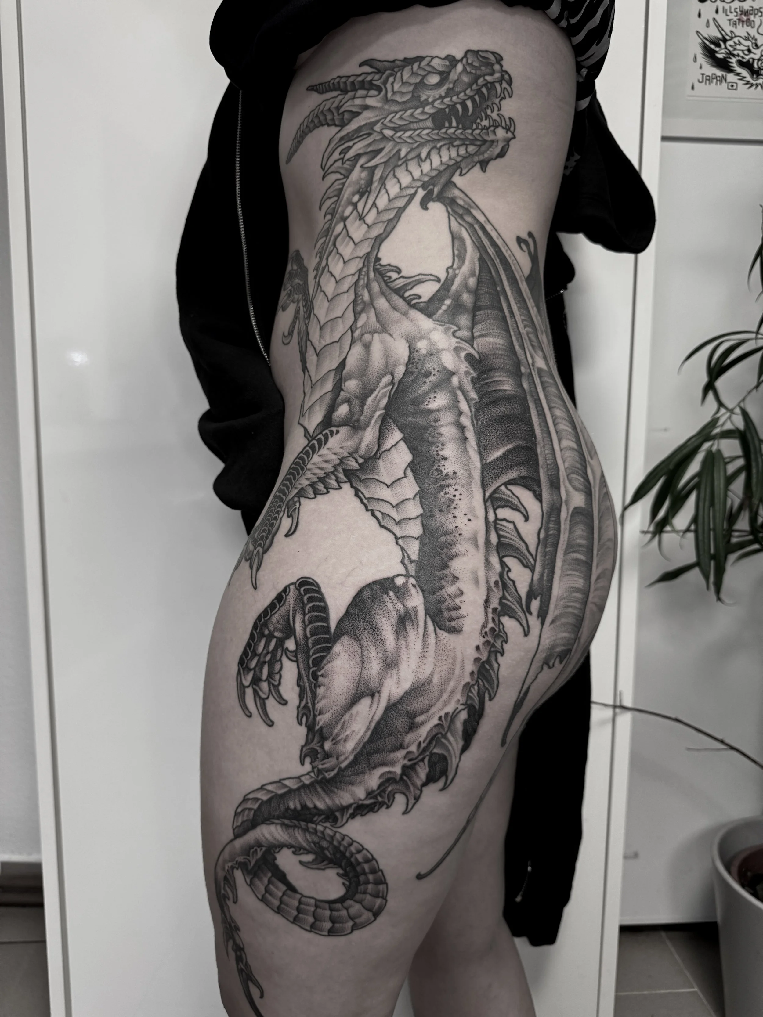 Schwarz-weiße Tätowierung eines Drachen, der die Seite eines Menschen bedeckt, mit detaillierten Schuppen, Flügeln und scharfen Zähnen.