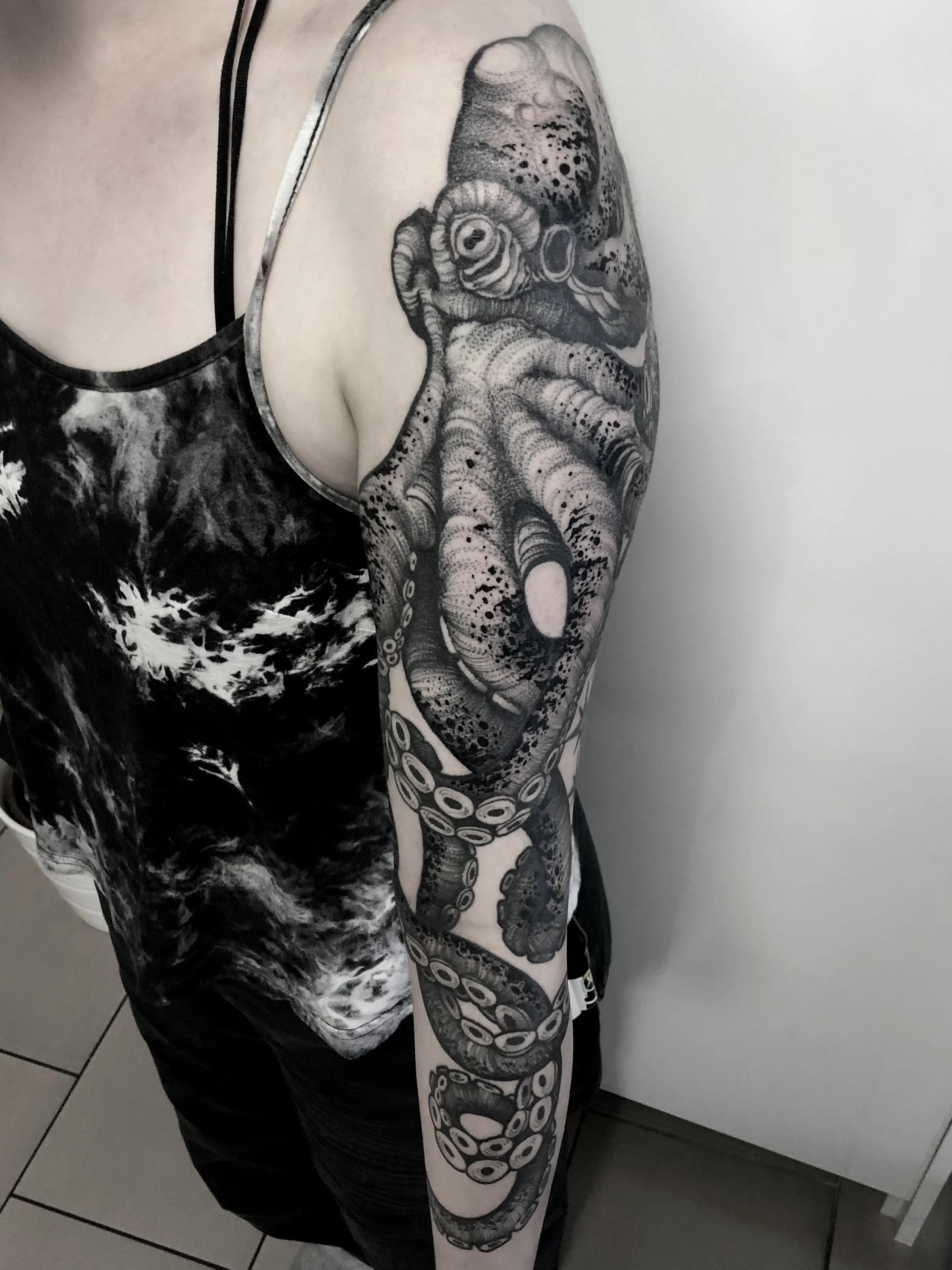 Schwarz-weiße Tätowierung eines Oktopus auf dem Arm einer Person.