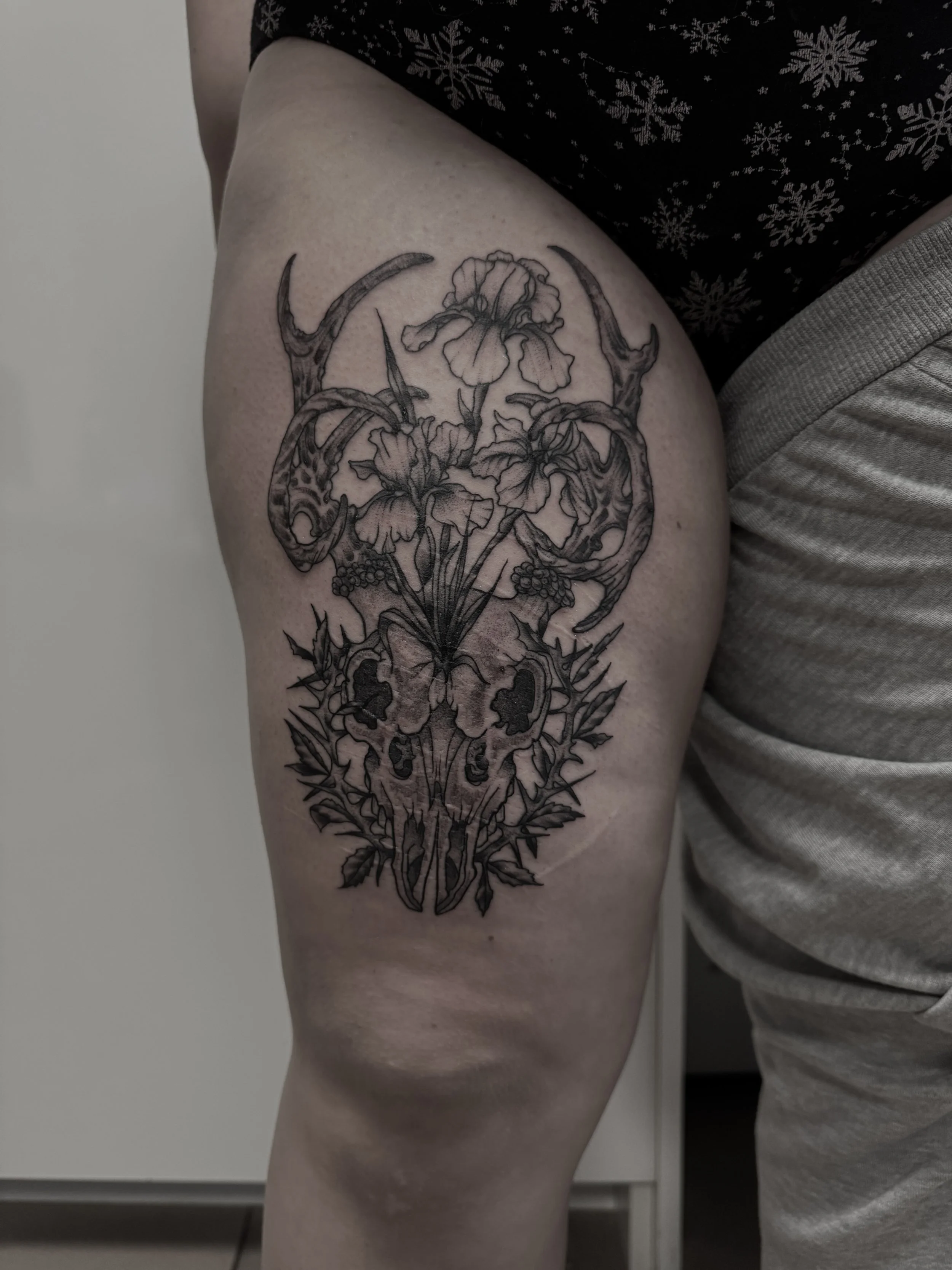 Tattoo eines Tierkopfes mit Blumen und antler auf Oberschenkel