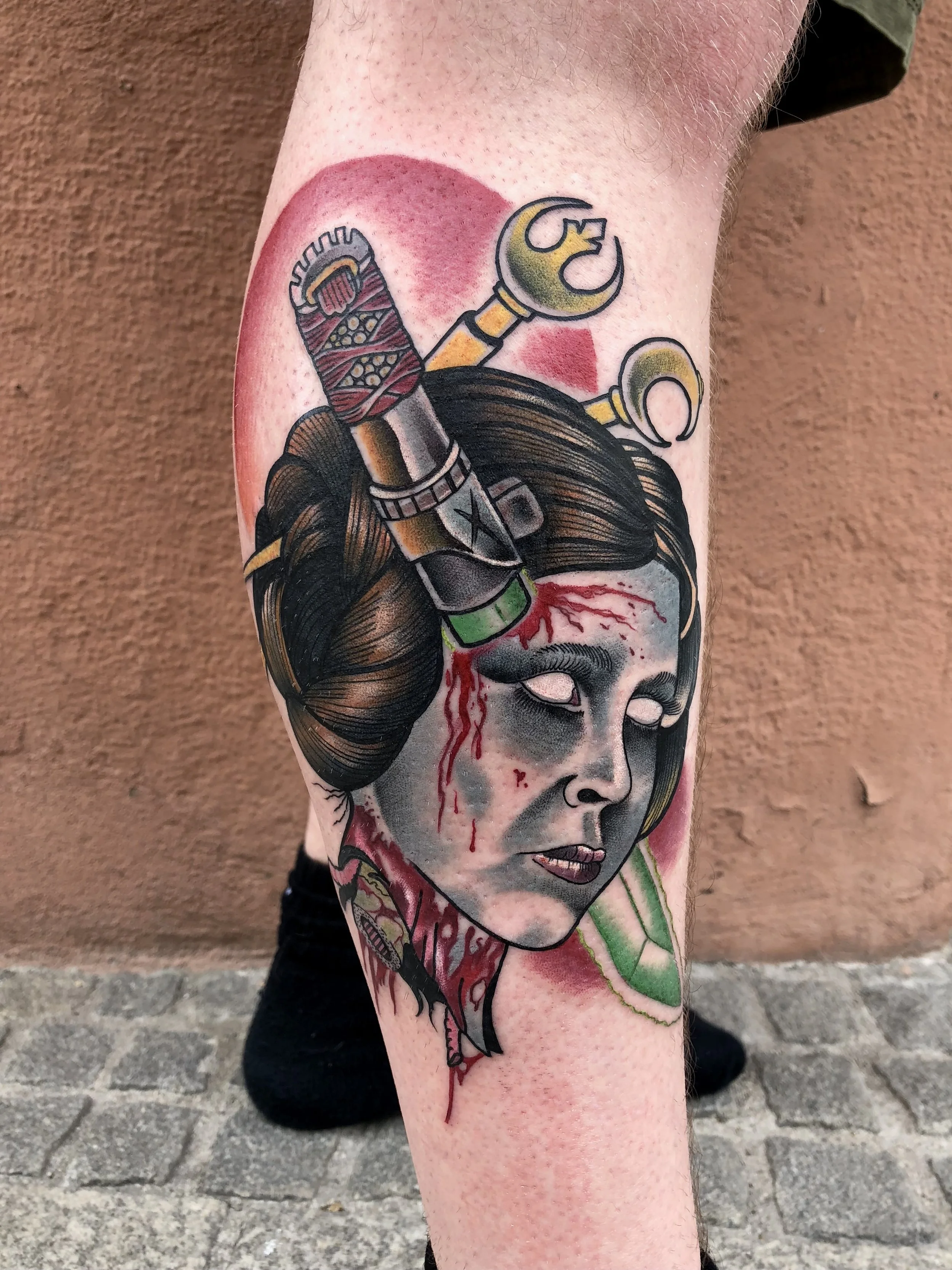 Tattoo eines japanischen Frauenkopfes mit blutigem Gesicht und traditionellen Frisuren und Accessoires, mit Werkzeugen wie einem Schraubenschlüssel und einem Schraubenzieher darüber.