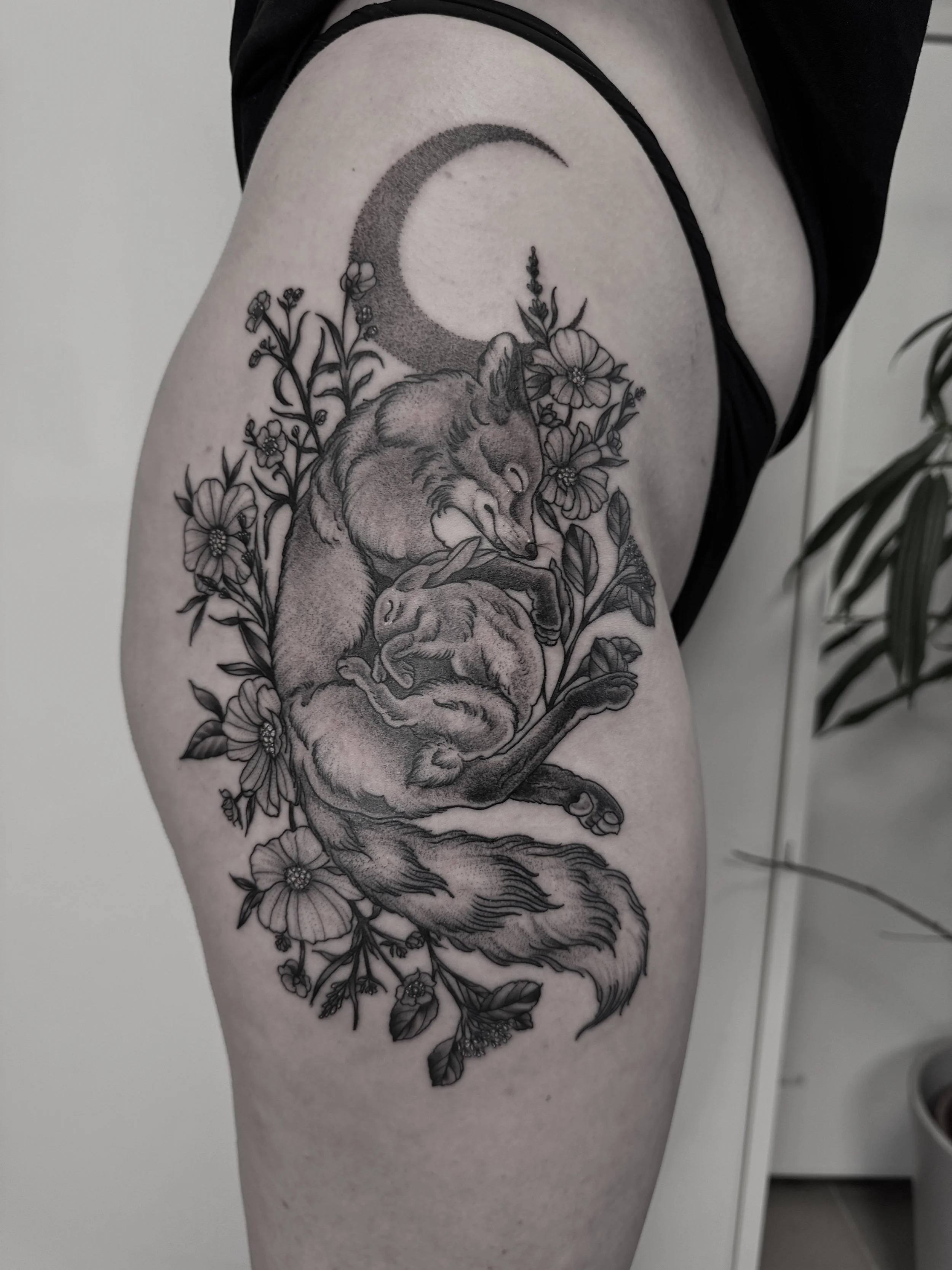 Tattoo eines Fuchses, umgeben von Blumen und einem Halbmond.