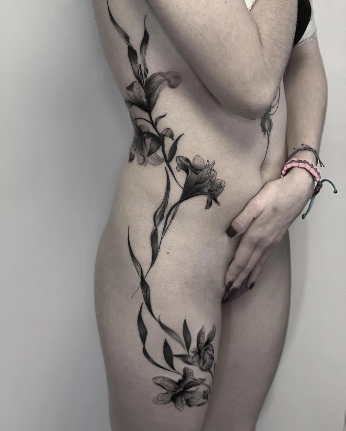 Nahaufnahme eines menschlichen Beins mit einer schwarzen Tätowierung eines Blumen- und Schmetterlingsdesigns.