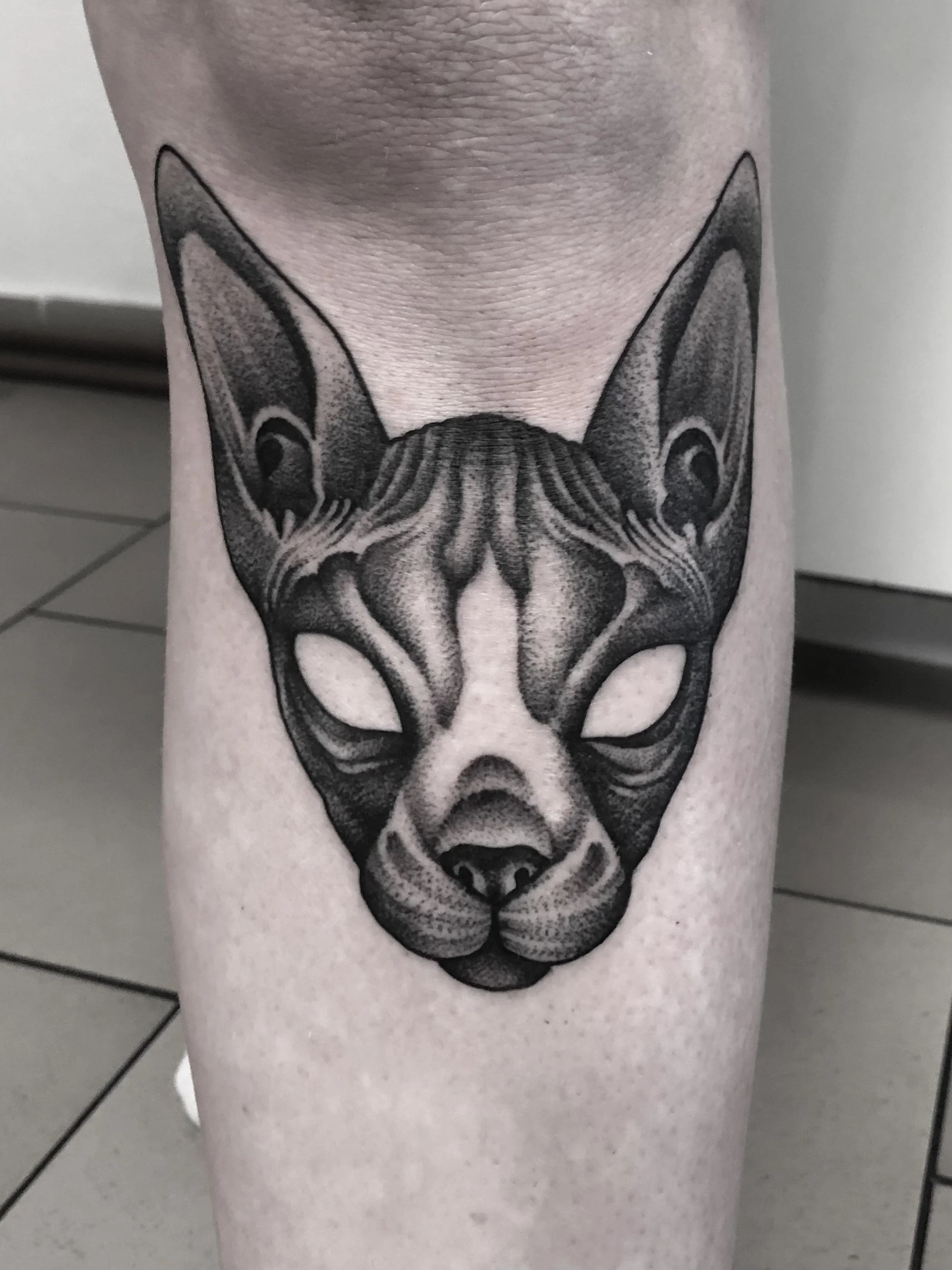 Schwarz-weiß-Tattoo eines Tierkopfs, der wie eine Mischung aus Hund und Fuchs aussieht, auf einem Oberschenkel.