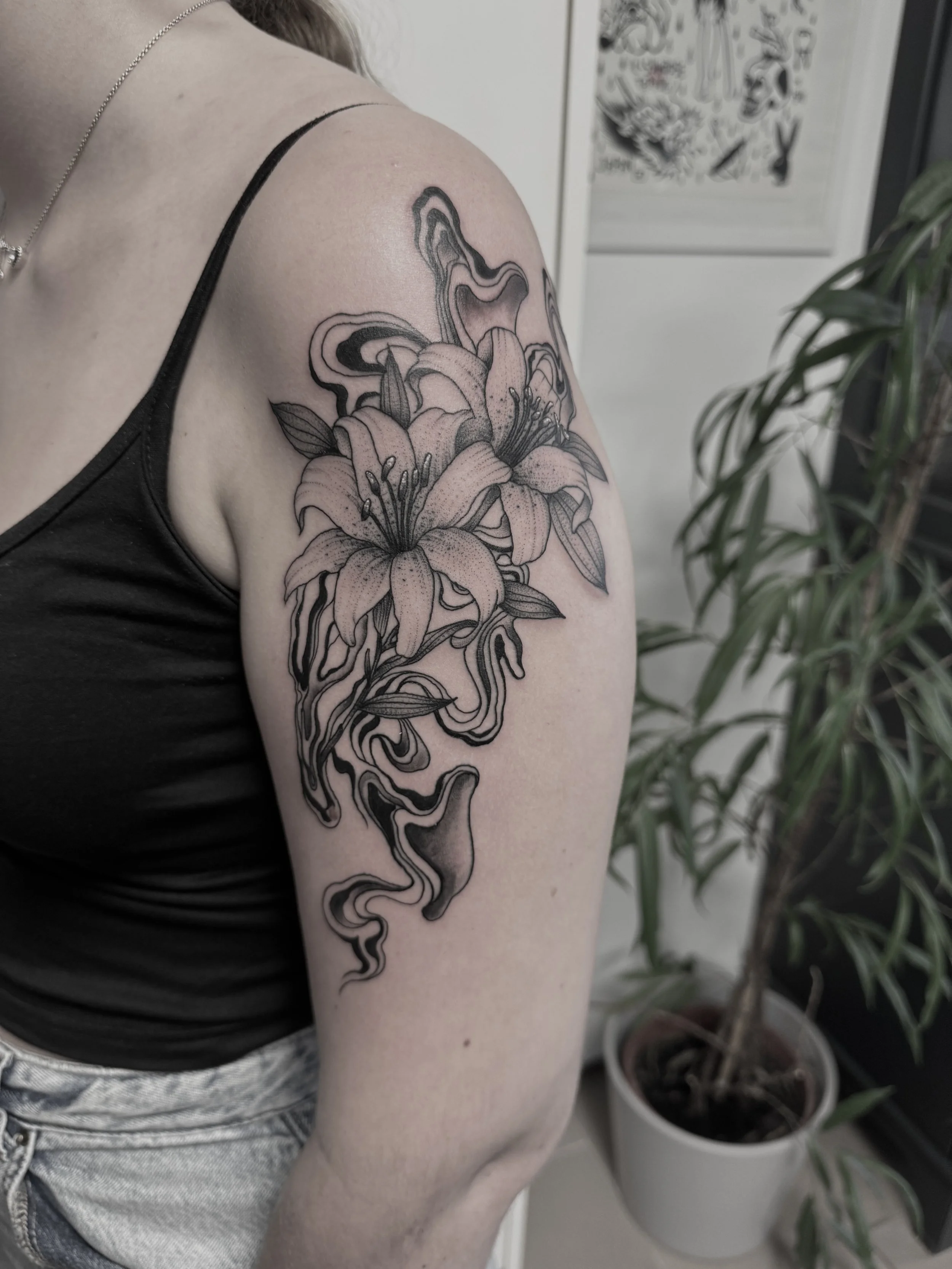 Schwarz-weiße Tätowierung eines Lilien- und Rosen-Designs auf dem Oberarm einer Person