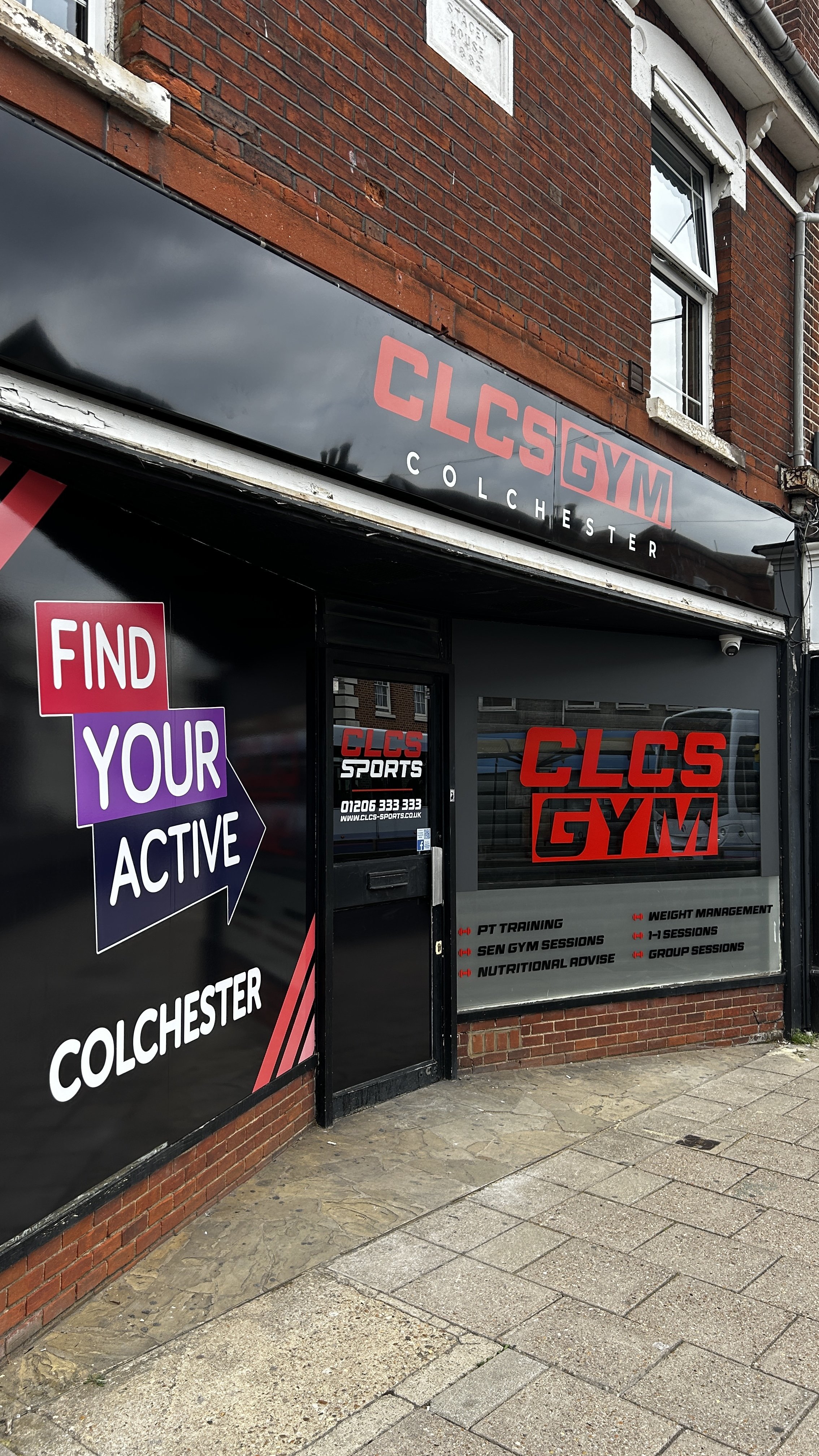 Exterior of a fitness center called CLC's GYM in Colchester with signage displaying services like PT training, gym sessions, nutritional advice, weight management, and group sessions, along with a motivational graphic saying 'Find Your Active'.