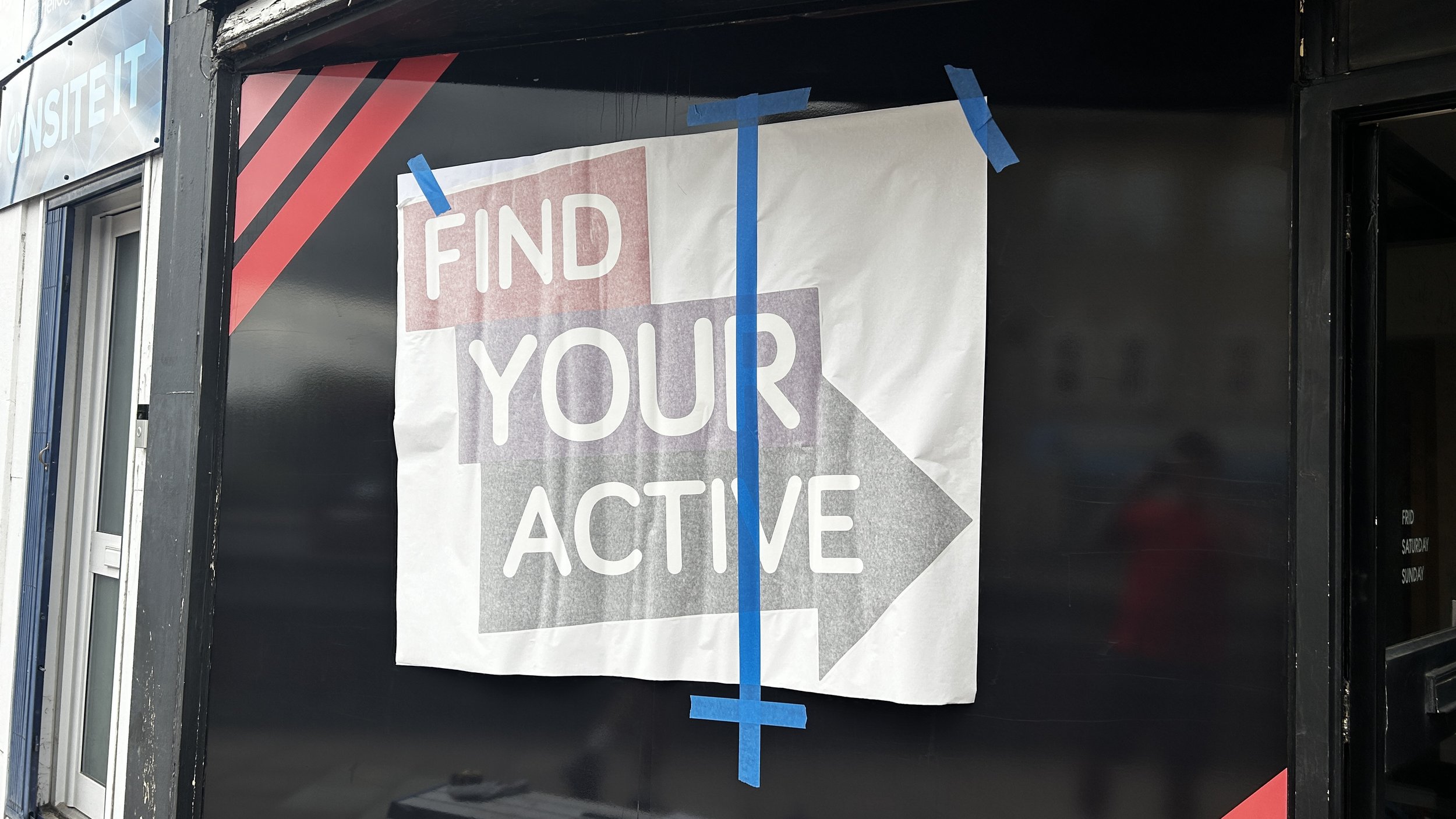 A sign taped to a black wall with blue painter's tape reads 'Find Your Active' with an arrow pointing to the right.