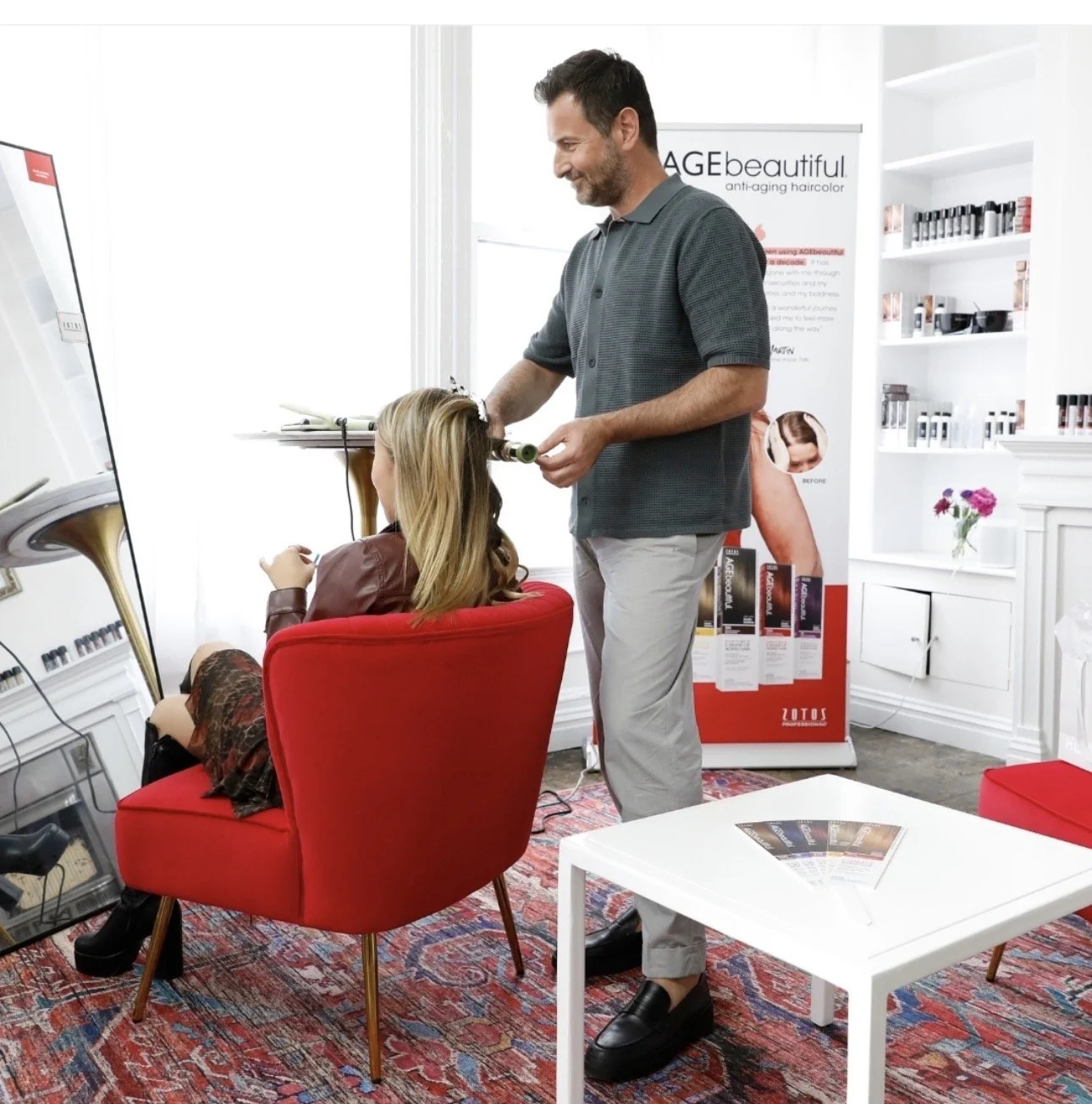 Celebrity Hairstylist Christopher Naselli giving touch-up styling at the AGEbeautiful media station. 