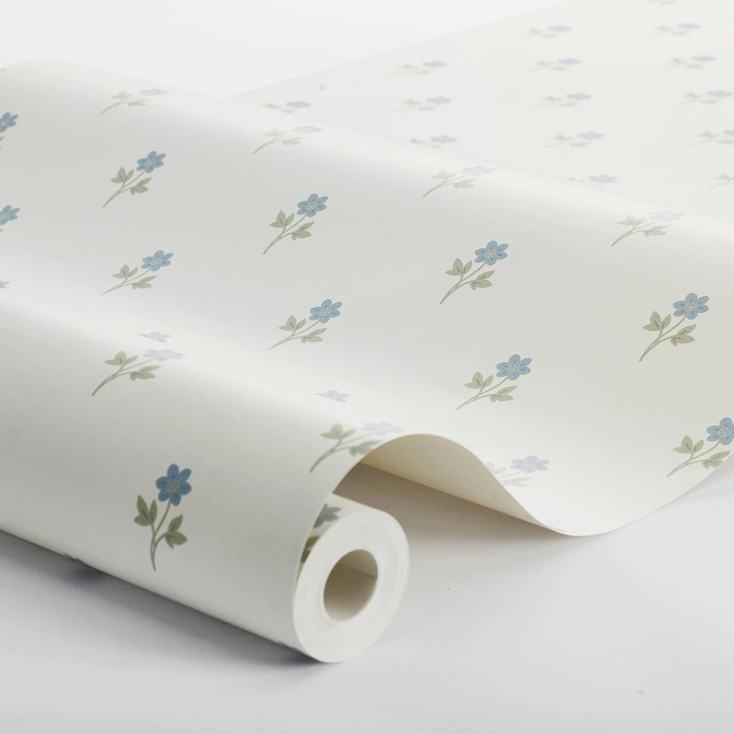 Schumacher Anemone wallpaper in Blue, unfurled on a roll to show the small-scale wood-anemone sprig pattern and paper texture, SKU 6974