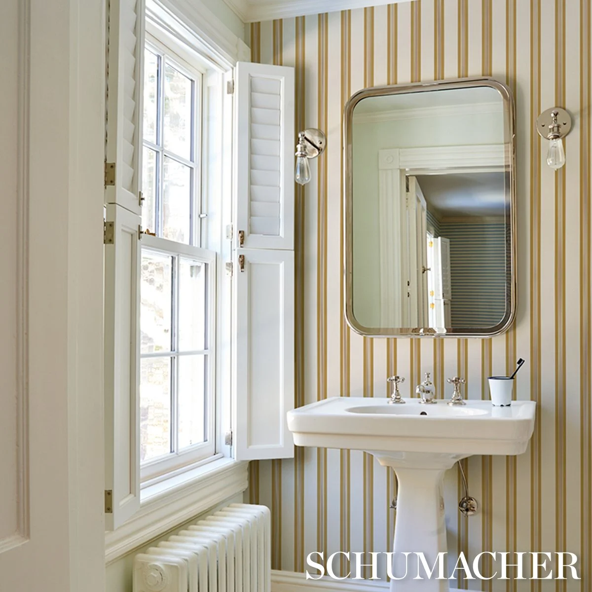 Schumacher Chatham Stripe wallpaper in Ochre in a powder room with pedestal sink and mirror