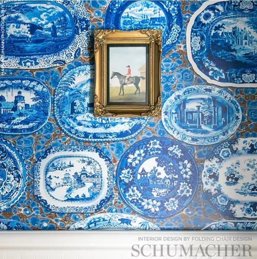 Ornate blue and white patterned wallpaper with a framed painting of a person on horseback hanging in the center.