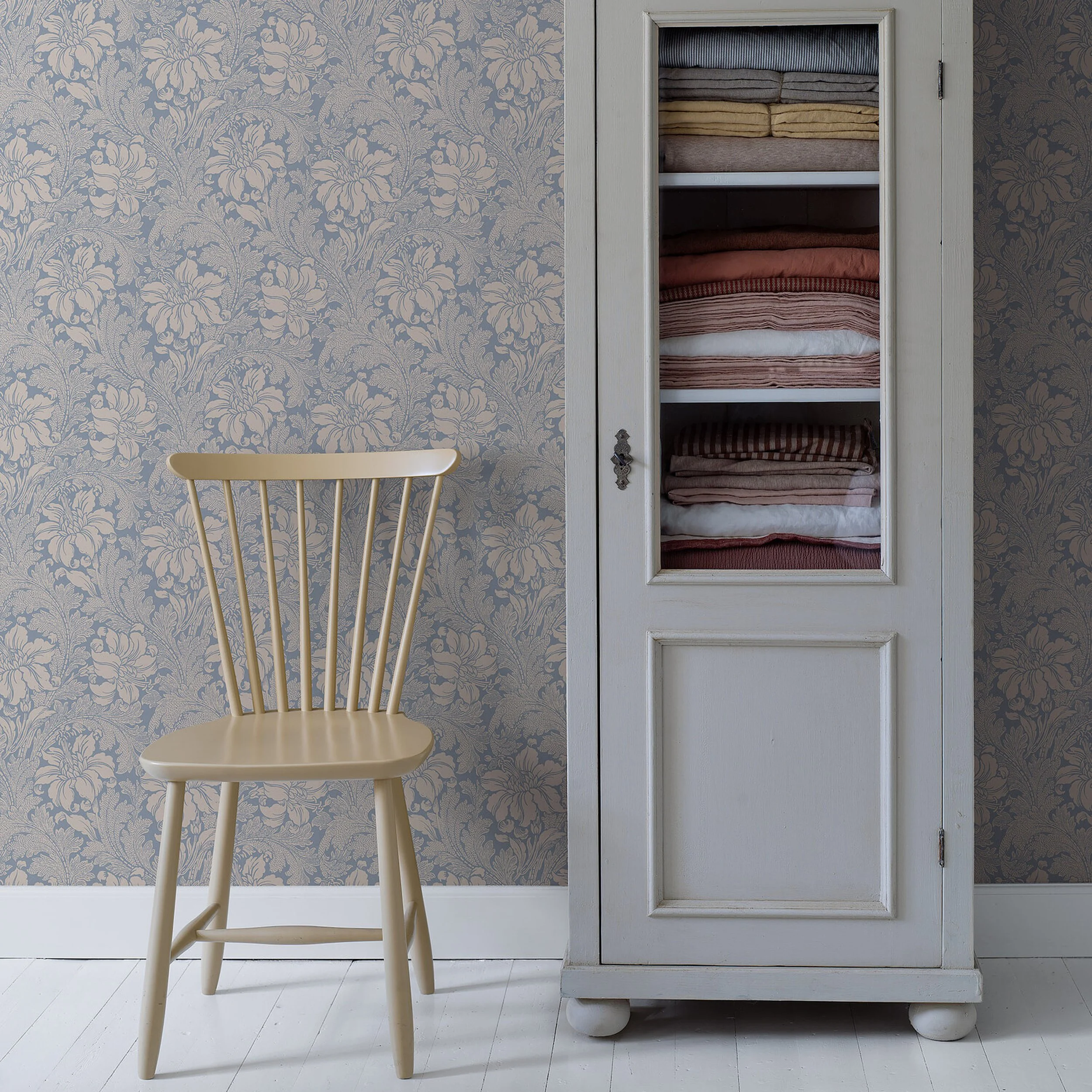 Schumacher Acanthus Garden Blue wallpaper in a room with a cream chair and linen cabinet, SKU 2010