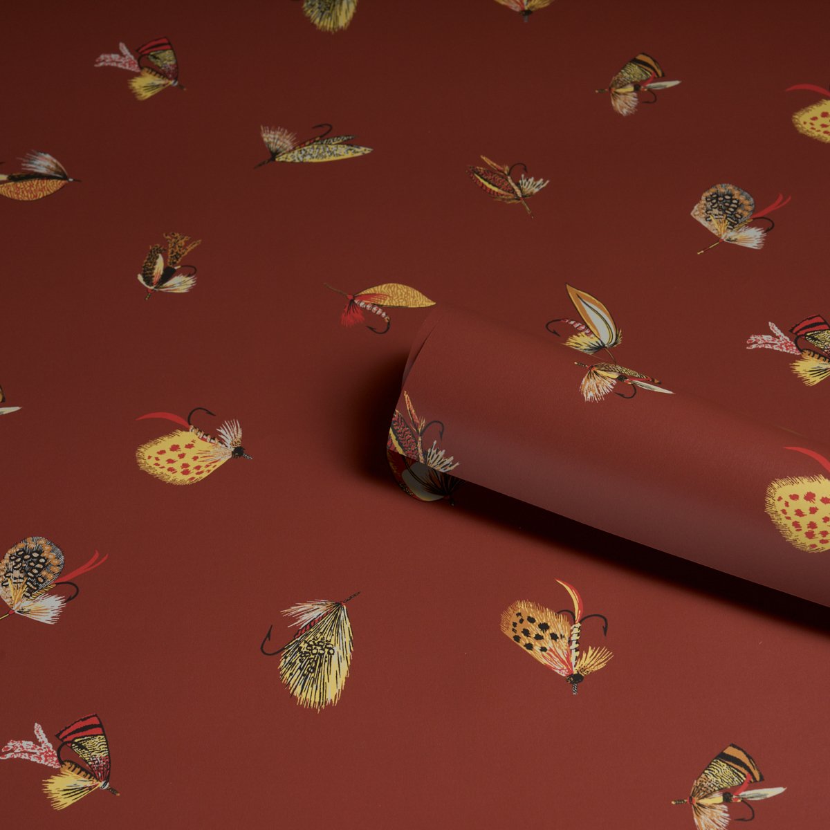 Schumacher Fly Fishing wallpaper roll in Russet, colorful feather flies on a deep red-brown ground