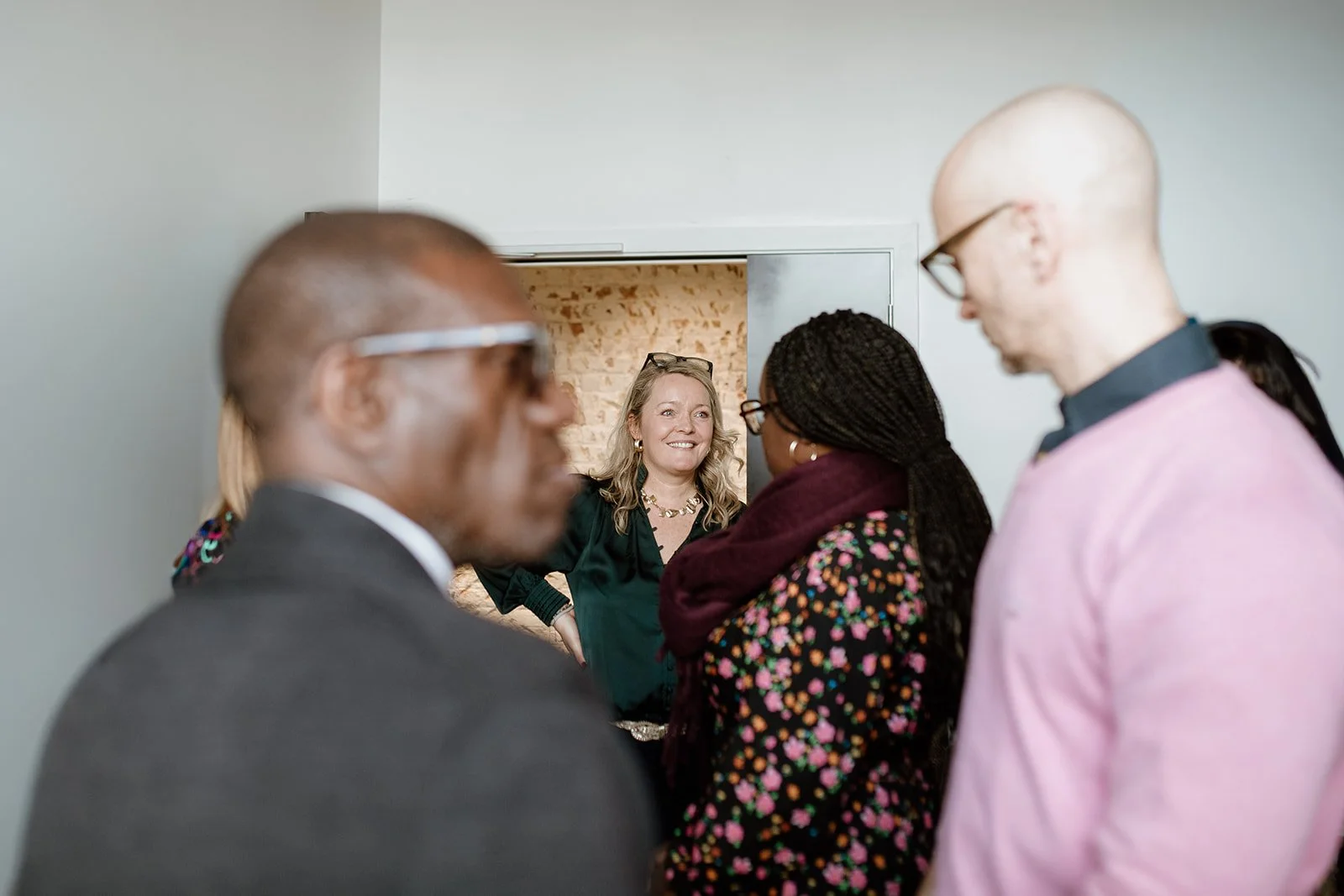 Lucy Timmons, coach, smiling and talking to a group of diverse people in an indoor setting.