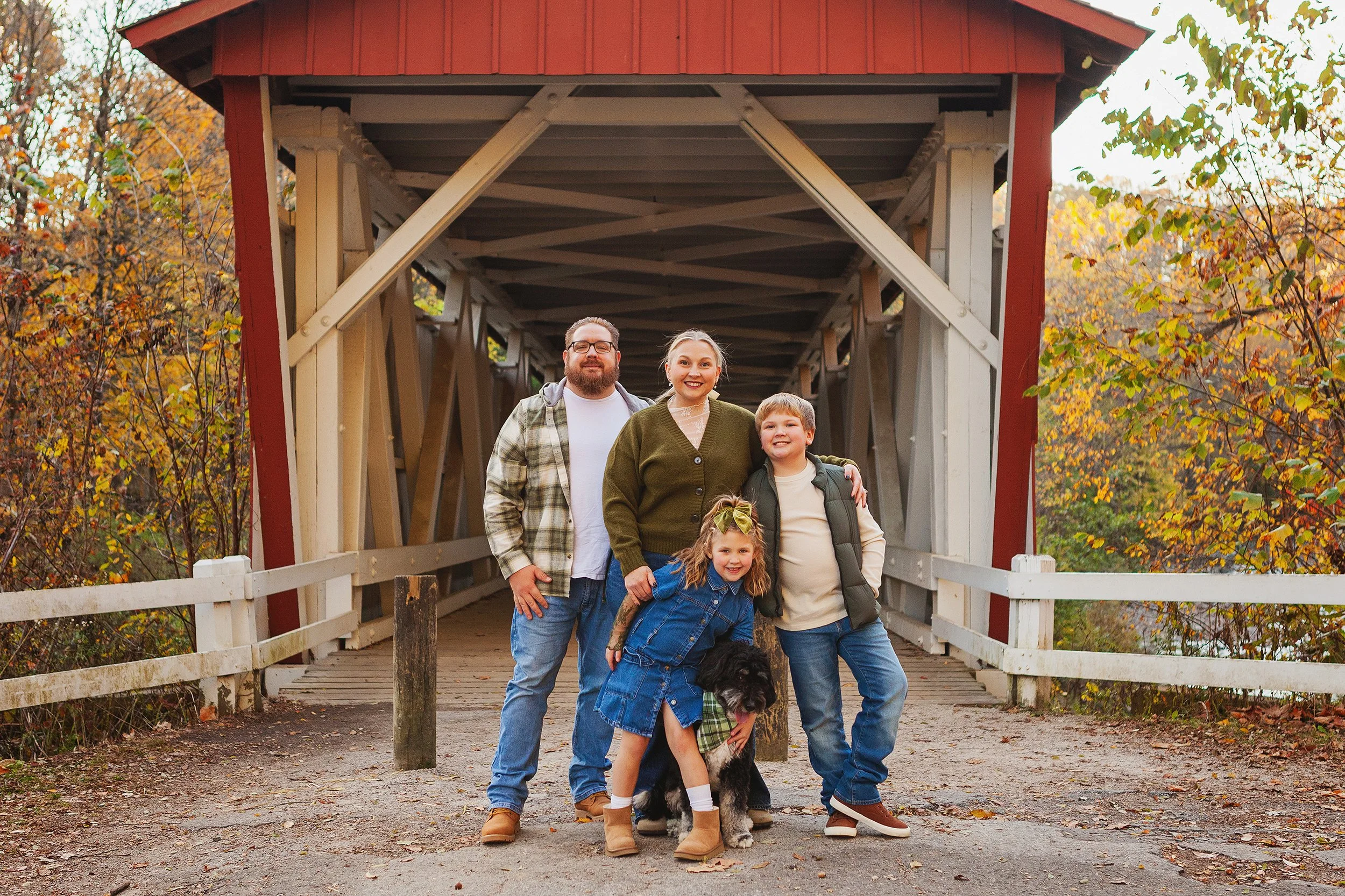 Family and dog posing under the Everett Road covered bridge in Peninsula, Ohio