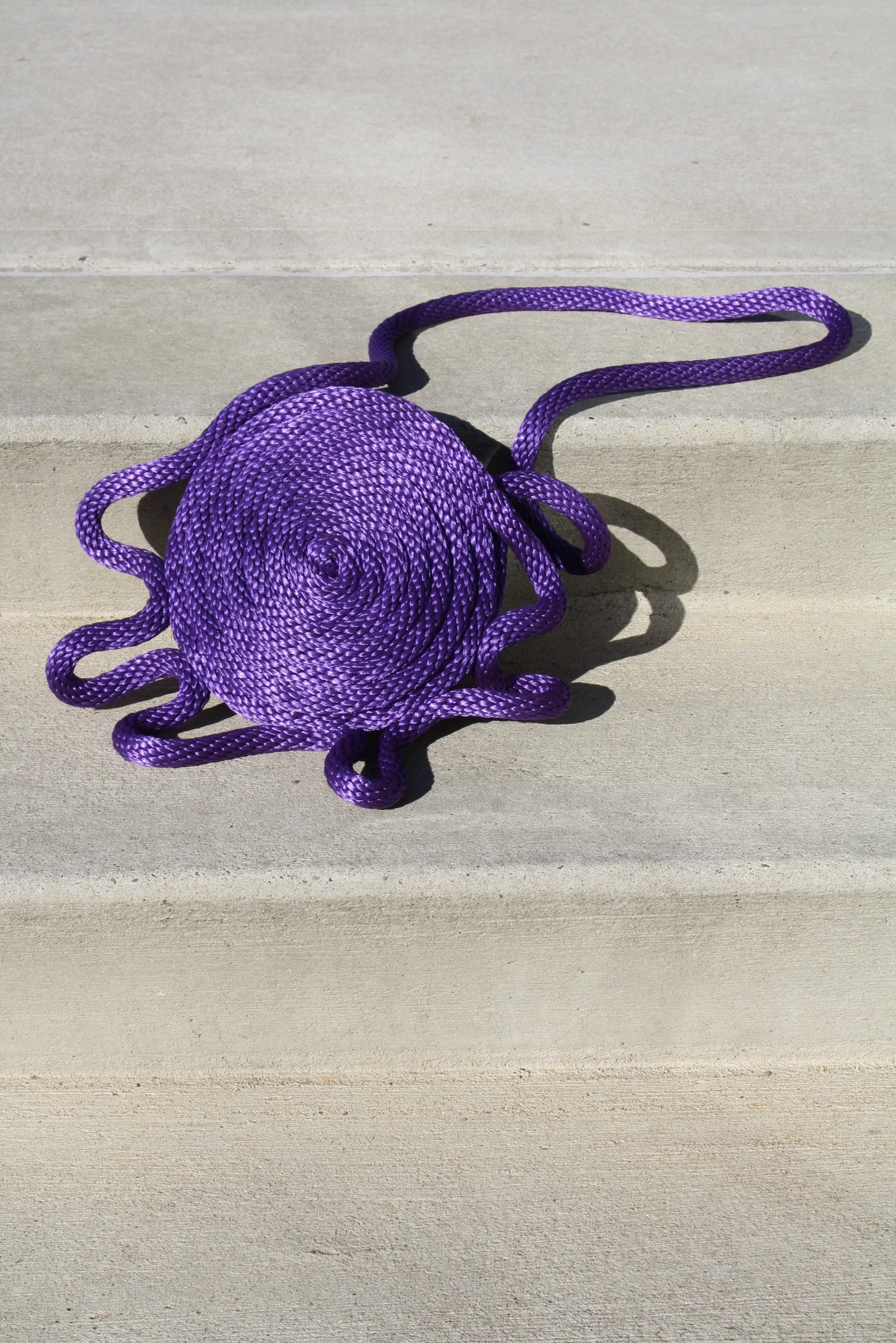 Purple coiled rope on a light beige stone surface.
