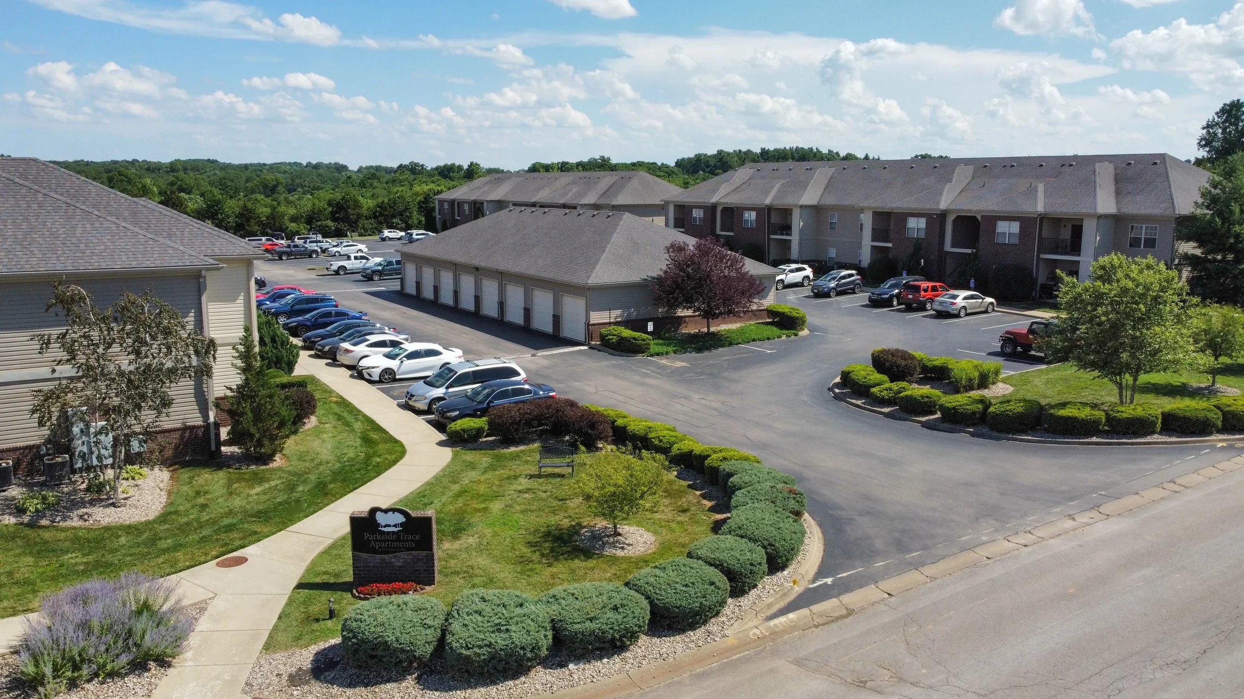 Aerial view of Parkside Trace Apartments with apartment buildings, parking lots, landscaped grounds, and surrounding trees.