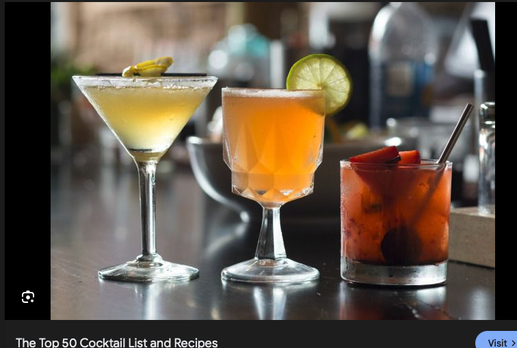 Three different cocktails on a bar counter, including a martini with a lemon twist, a citrus drink with a lime garnish, and a red-colored cocktail with fruit slices.