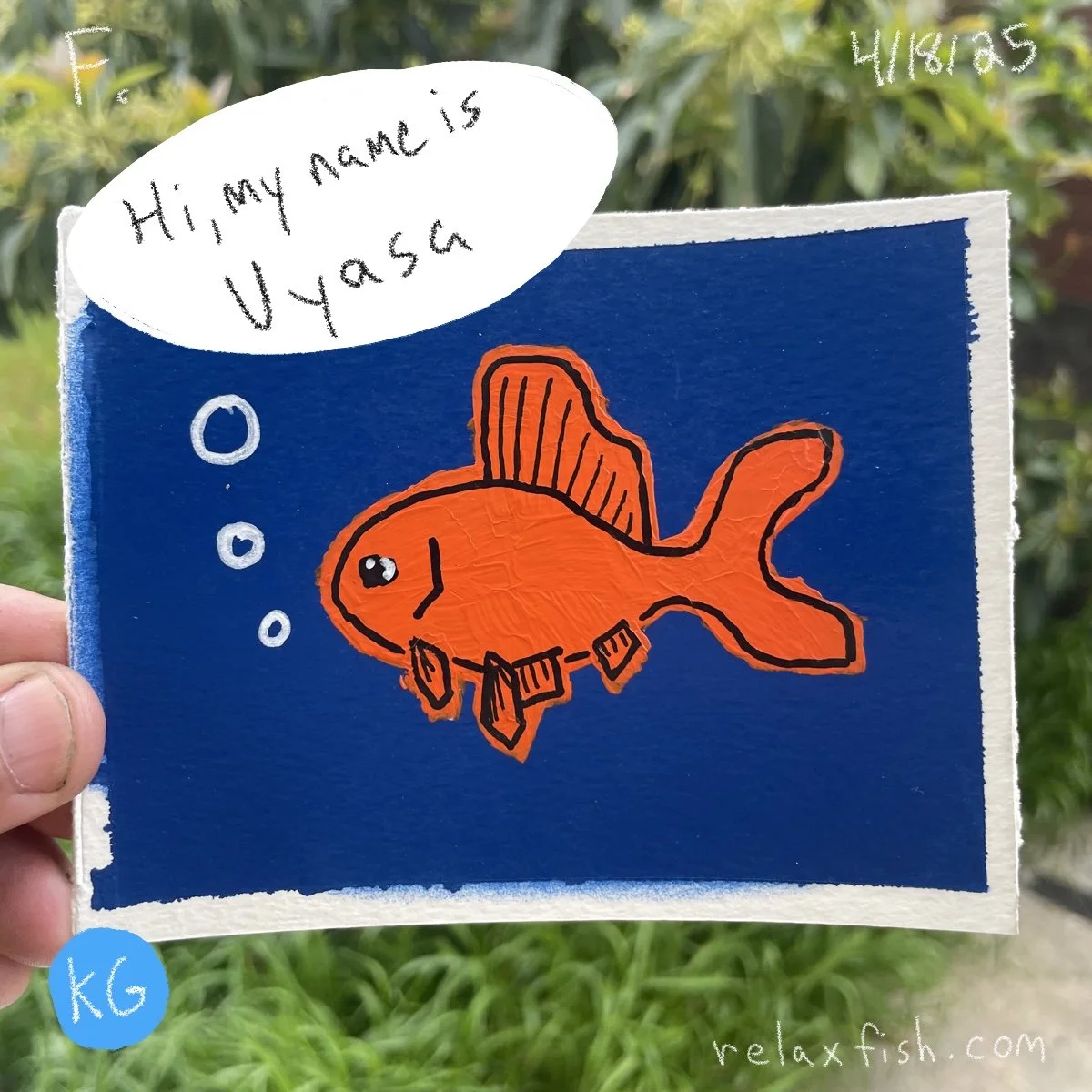 A drawing of an orange fish with black outline and fins, floating in a blue background with bubbles. A speech bubble says, "Hi, my name is Uyasa." There is a blue sticker with "KG" on it and the website relaxfish.com in the bottom right corner.