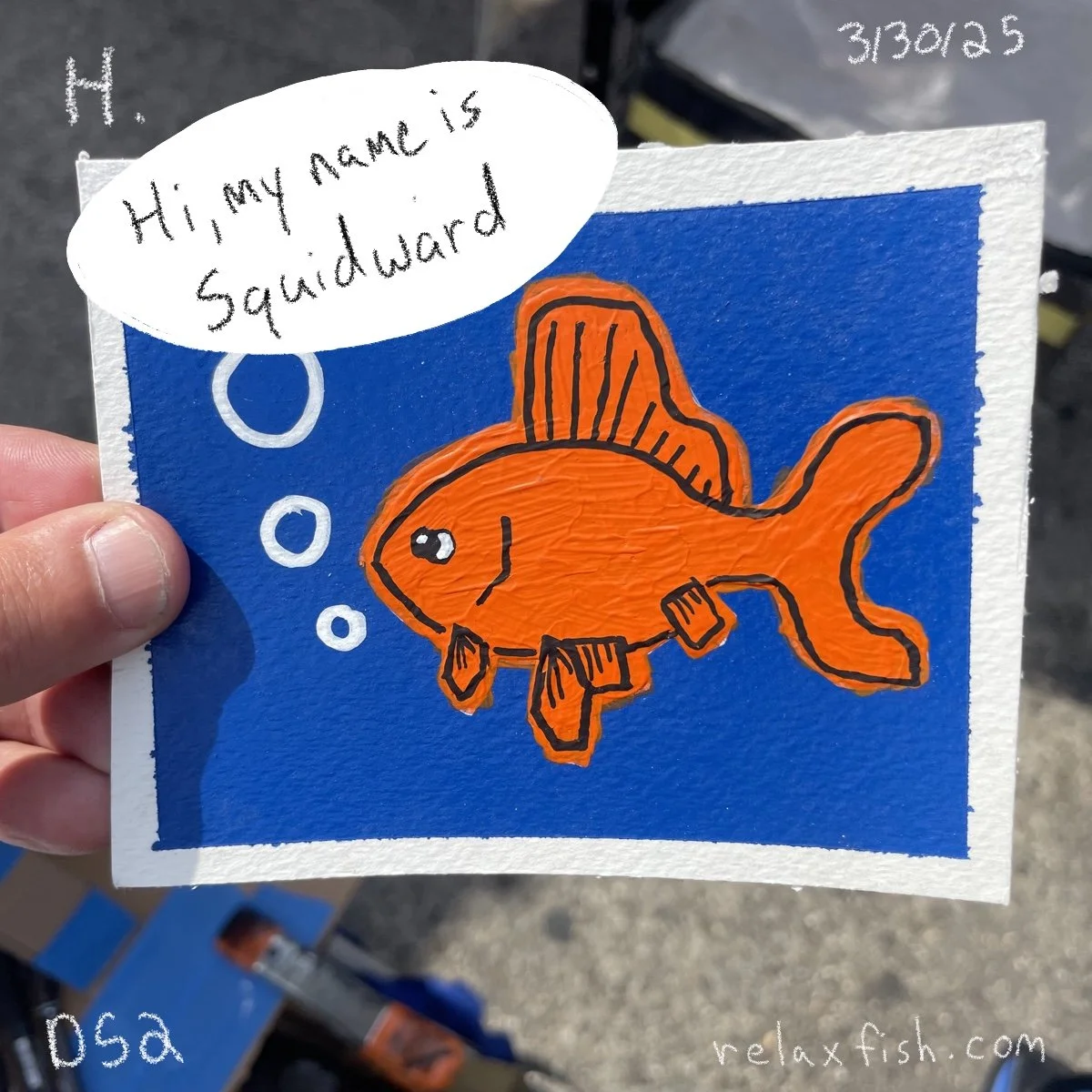 A drawing of a bright orange fish with black outlines against a blue background. The fish has fins and a smiling face. There is a speech bubble above the fish that reads, 'Hi, my name is Squidward.' The image includes some handwritten numbers and a w