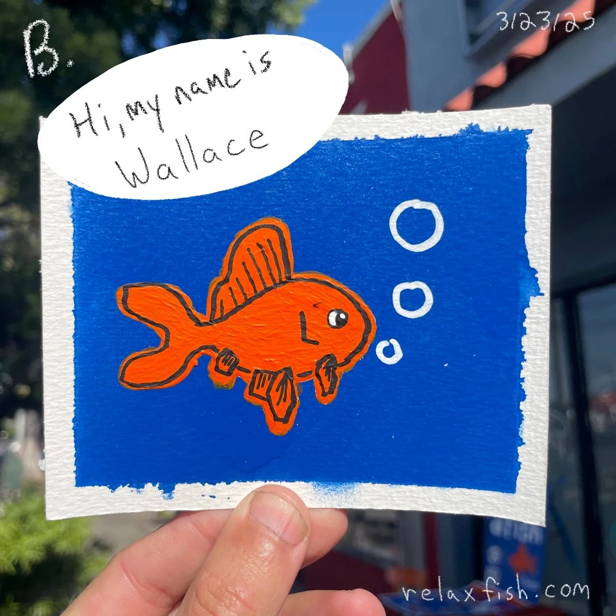Colorful drawing of an orange fish with fins and bubbles on a blue background. A speech bubble at the top left says, 'Hi, my name is Wallace.' Hand holding the drawing and outdoor scene in the background. Relaxfish.com text at the bottom right.
