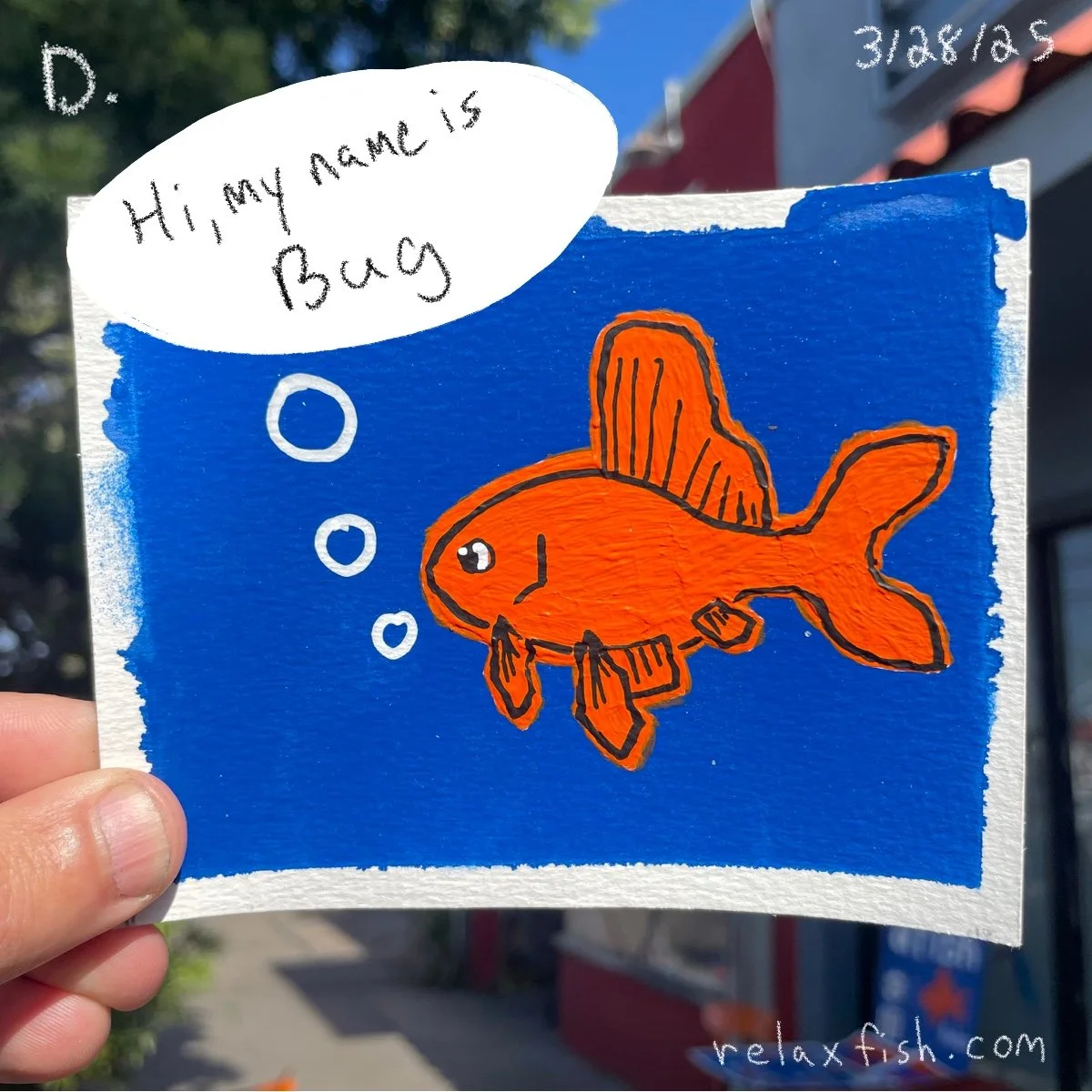 A drawing of an orange fish with black outlines against a blue background. The fish has a fin on its back and a tail, with bubbles coming from its mouth. A speech bubble says, "Hi, my name is Buck." The drawing appears to be on a piece of textured pa