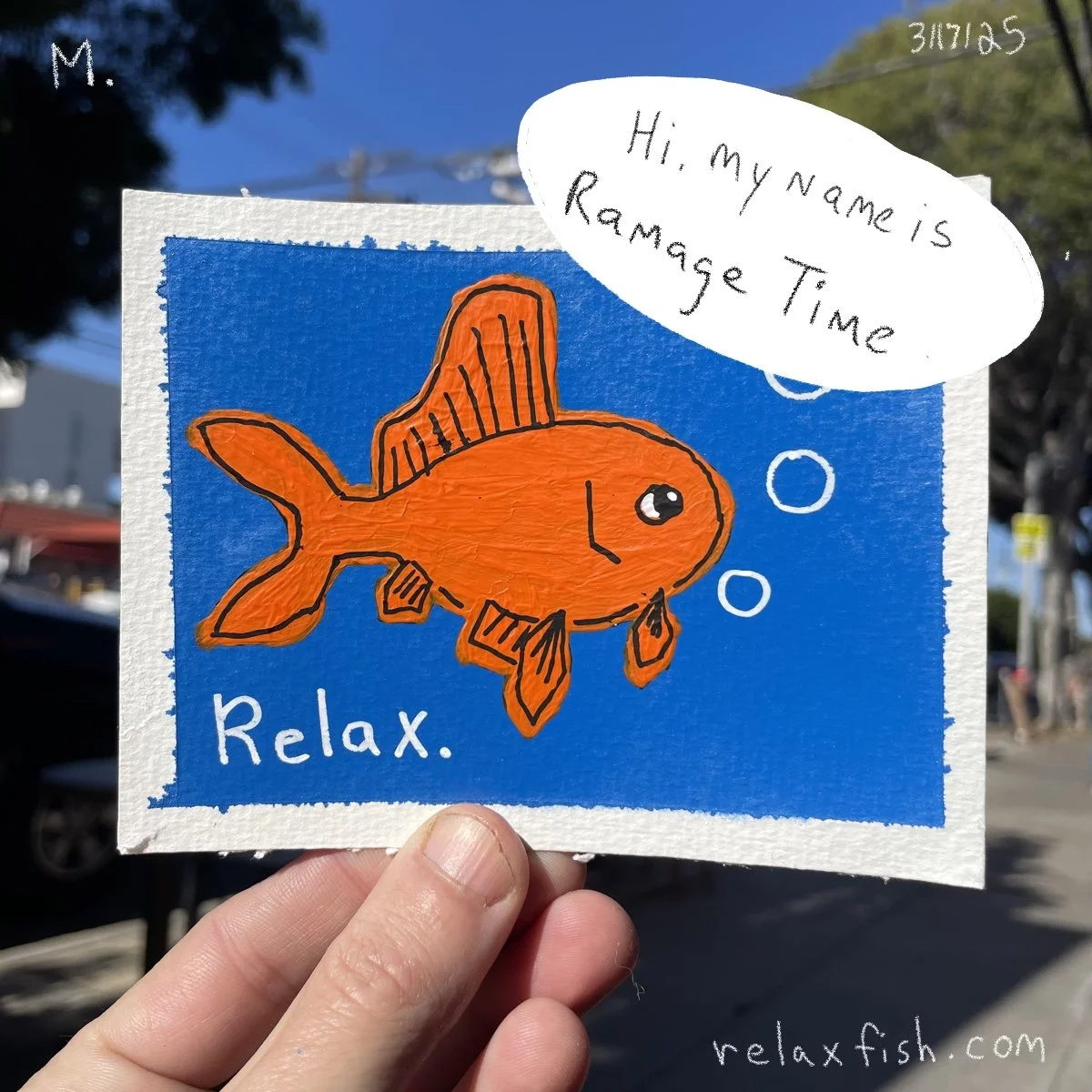 A hand holding a colorful handmade card with a drawing of an orange fish with fins and bubbles. The card has blue and white background, and the text reads: 'Relax.' The fish has a speech bubble that says, 'Hi, my name is Rammage Time.'