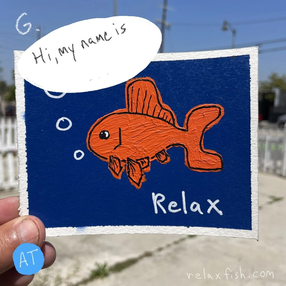Handheld sign featuring a colorful cartoon fish with a speech bubble saying "Hi, my name is" and the word "Relax" underneath, with a website address relaxfish.com in the bottom right corner.