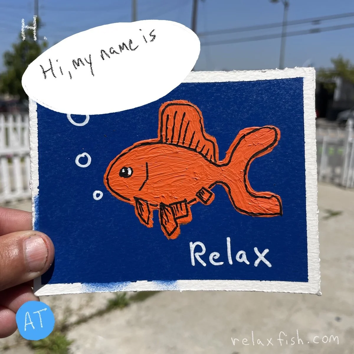 A colorful drawing of an orange fish wearing a scuba diving mask, with bubbles rising to the surface. The fish is set against a dark blue background with the word 'Relax' written below. There is a speech bubble above the fish saying 'Hi, my name is,'