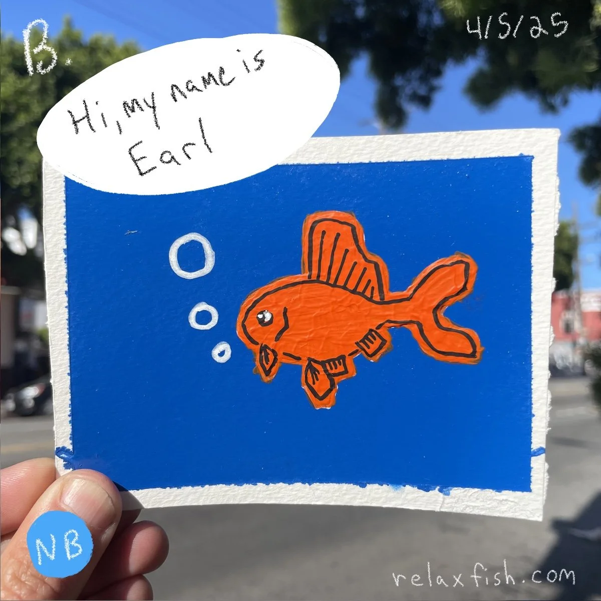 A hand holding a drawing of an orange fish with fins and a big eye, set against a blue background. The drawing includes speech bubbles and text, with the speech bubble saying 'Hi, my name is Earl.' Handwritten notes in the corners include '4/5/25' in