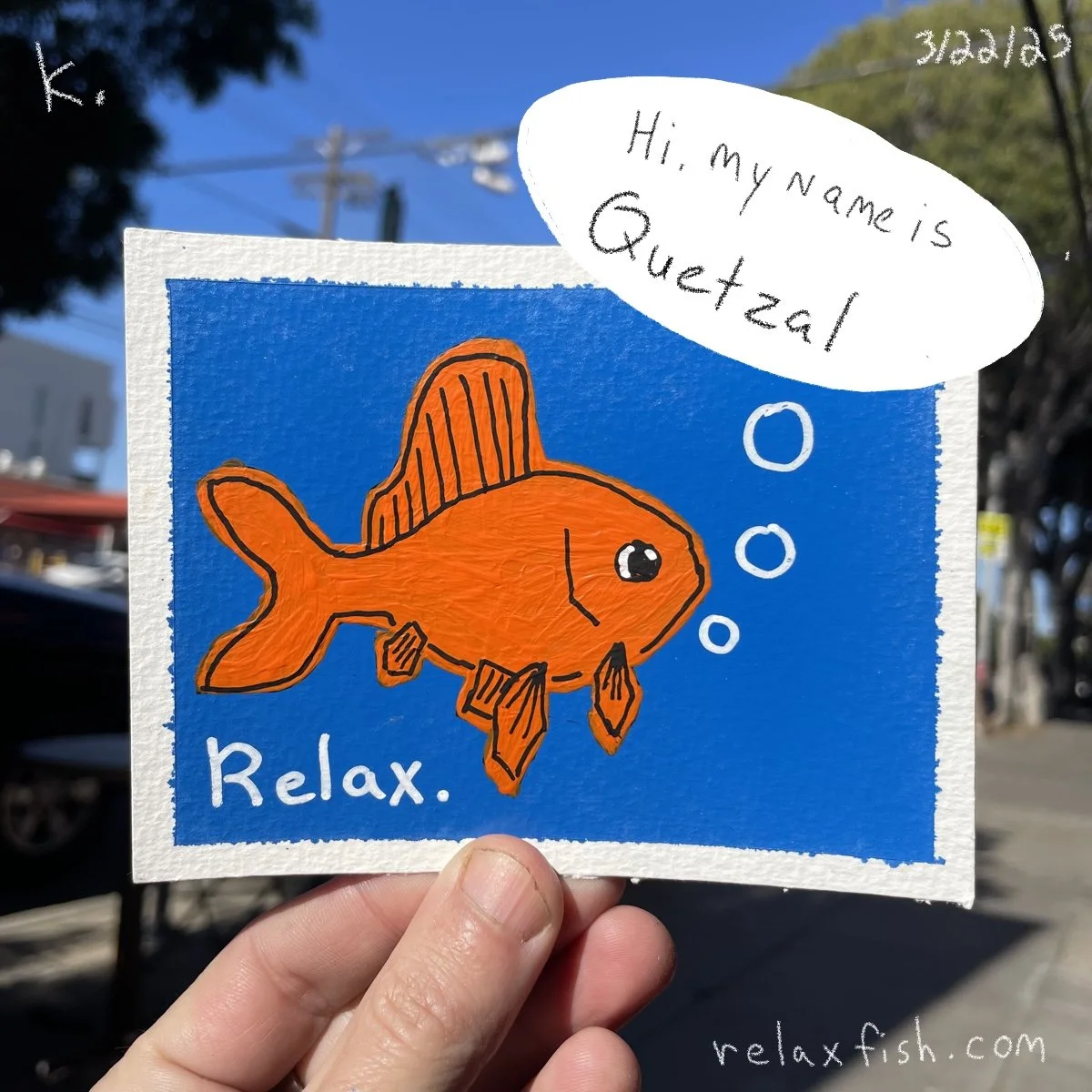 Colorful hand-drawn sign featuring an orange fish with black outlines and fins, floating in blue water with bubbles. The sign reads 'Relax.' and has a speech bubble that says 'Hi, my name is Quetzel'. The date '3/26/23' and website 'relaxfish.com' ar