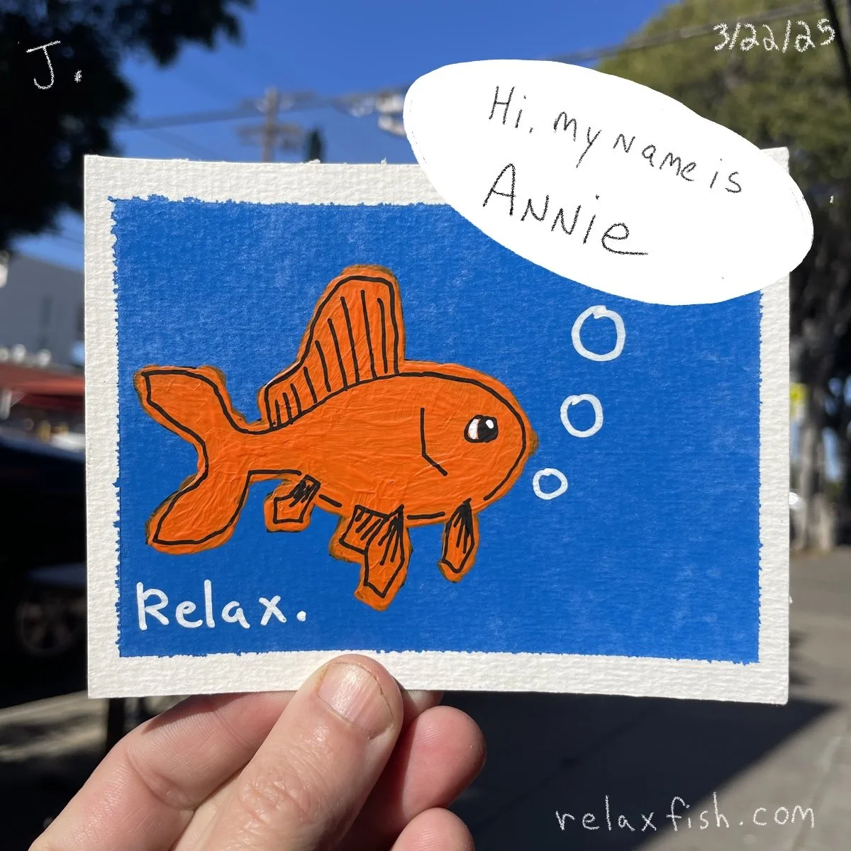 A colorful drawing of an orange fish with black outlines on a blue background. The fish has a speech bubble that says, 'Hi, my name is Annie.' The word 'Relax.' is written at the bottom left, and the website 'relaxfish.com' is at the bottom right. Th