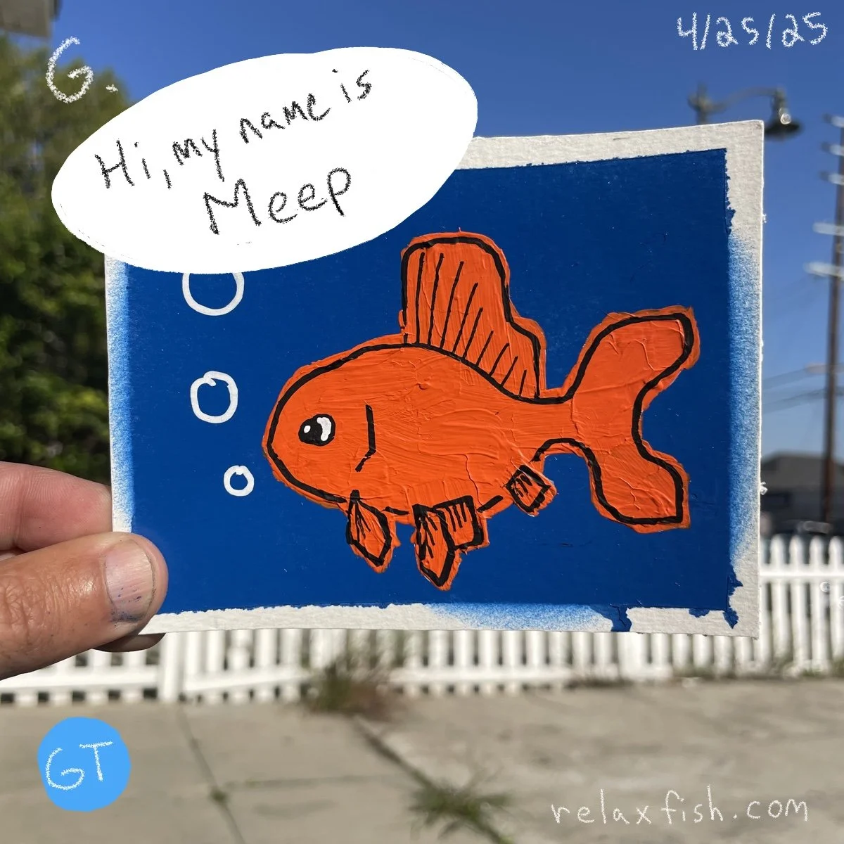 Colorful drawing of an orange fish with black outlines, bubbles, and a speech bubble saying 'Hi, my name is Meep.' The drawing is held in front of a sunny outdoor background with a white picket fence and power lines, date 4/25/25, and website relax.f