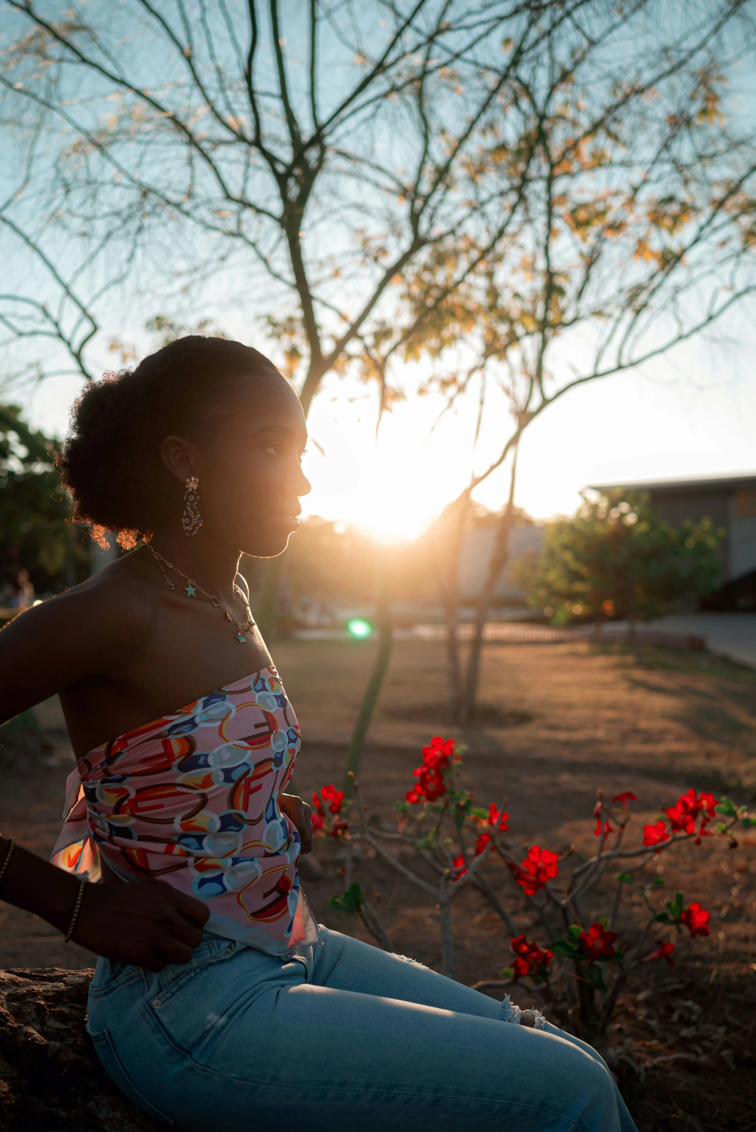 Young woman standing in a yard next to flowers.