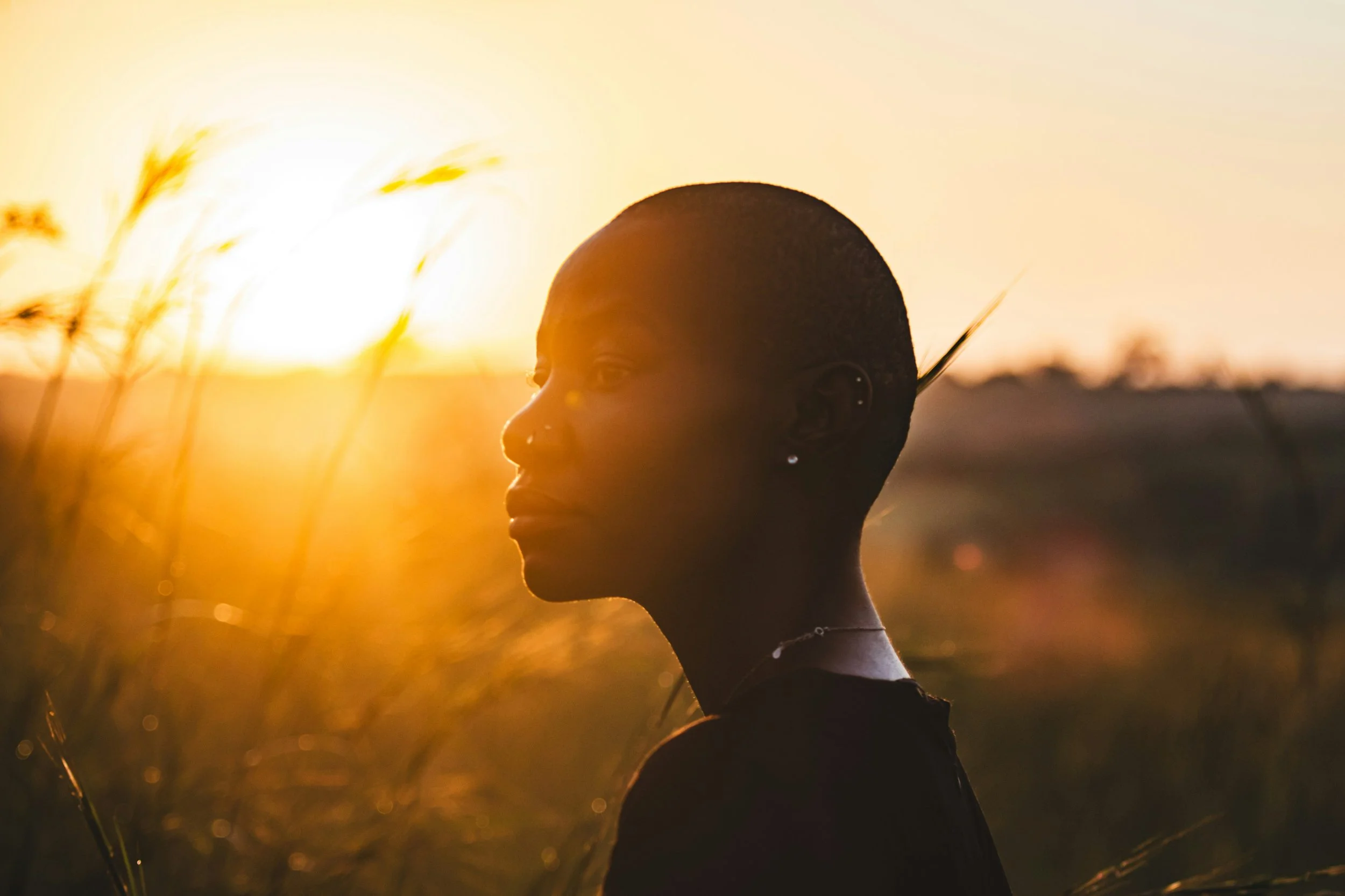 Young woman's portrait standing in nature with sunlight in background.