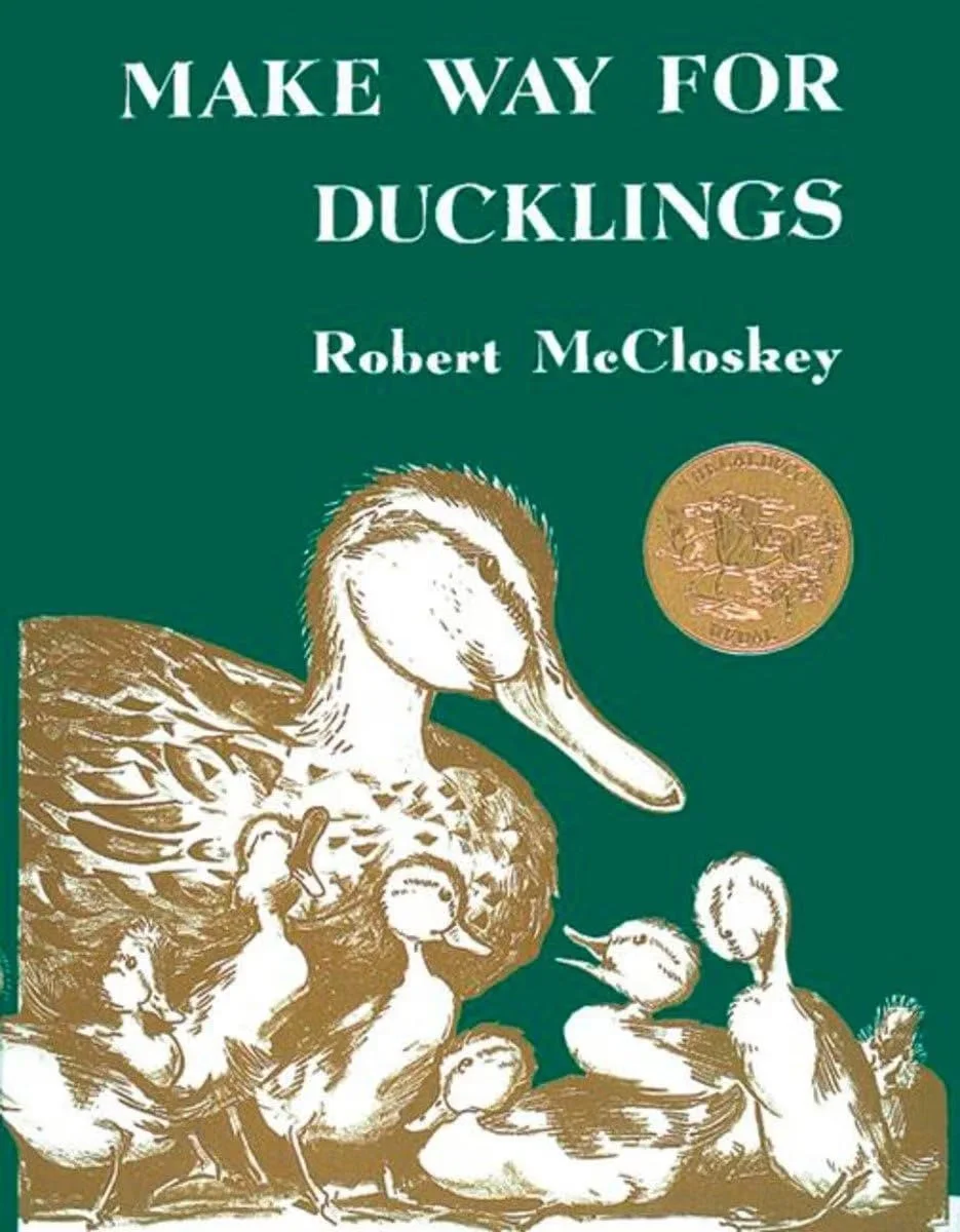 The cover of a book titled 'Make Way for Ducklings' by Robert McCloskey, featuring an illustration of a mother duck with ducklings on a green background, with a gold medal in the top right corner.