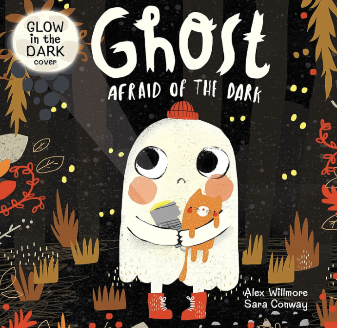 Cover of a children's book titled 'Ghost Afraid of the Dark' showing a cute ghost with big eyes wearing red boots and a red hat, holding a flashlight and an orange cat. The background is a dark forest with colorful leaves and plants, illuminated by small glowing dots.