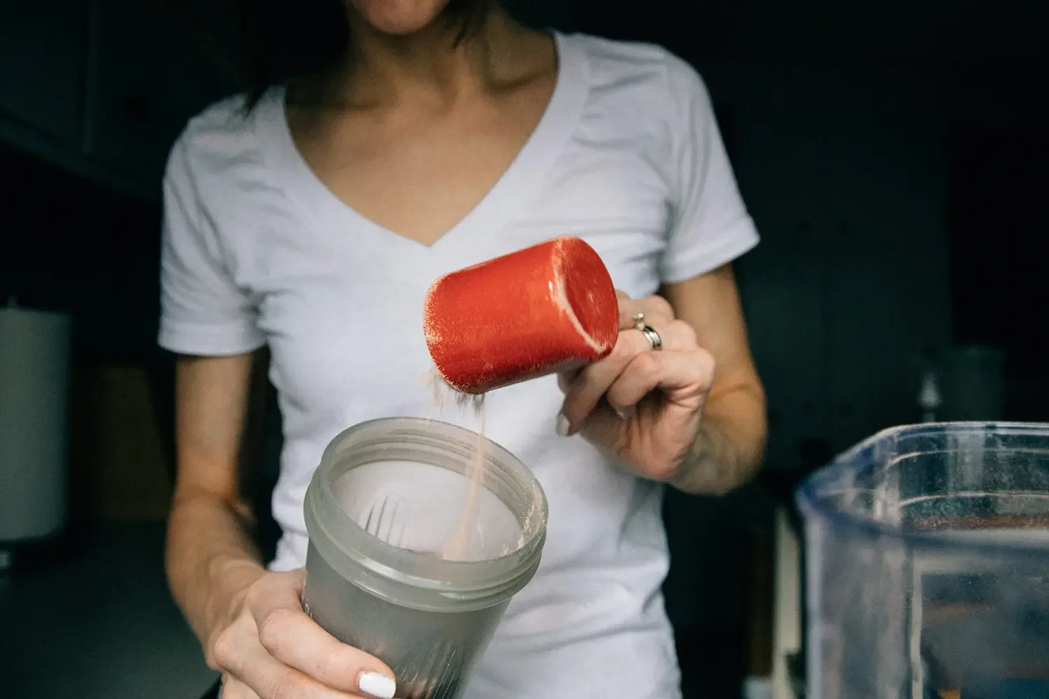 A woman is putting protein powder into a shaker.