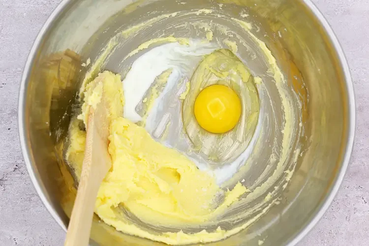 Egg and milk added to creamed butter and sugar in a mixing bowl