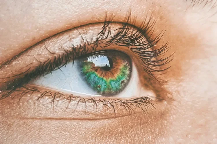 An extreme close-up of a woman's vivid green eye, focusing on the intricate details of the iris and pupil, representing vision clarity and ocular health.