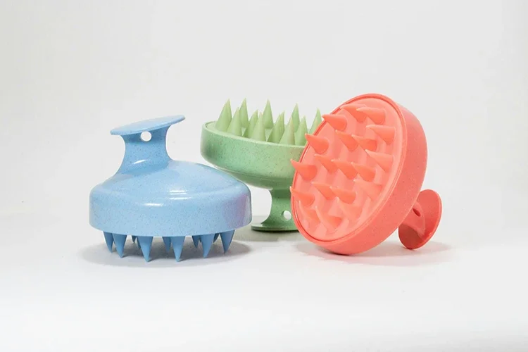 Three scalp massagers of different colors placed on a white background.