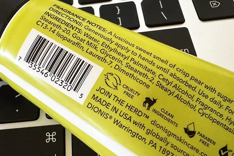 A close-up photo of a skincare product's back label showing the Cruelty-Free bunny icon, Clean Ingredients mark, and Paraben-Free seal, placed on a computer keyboard.