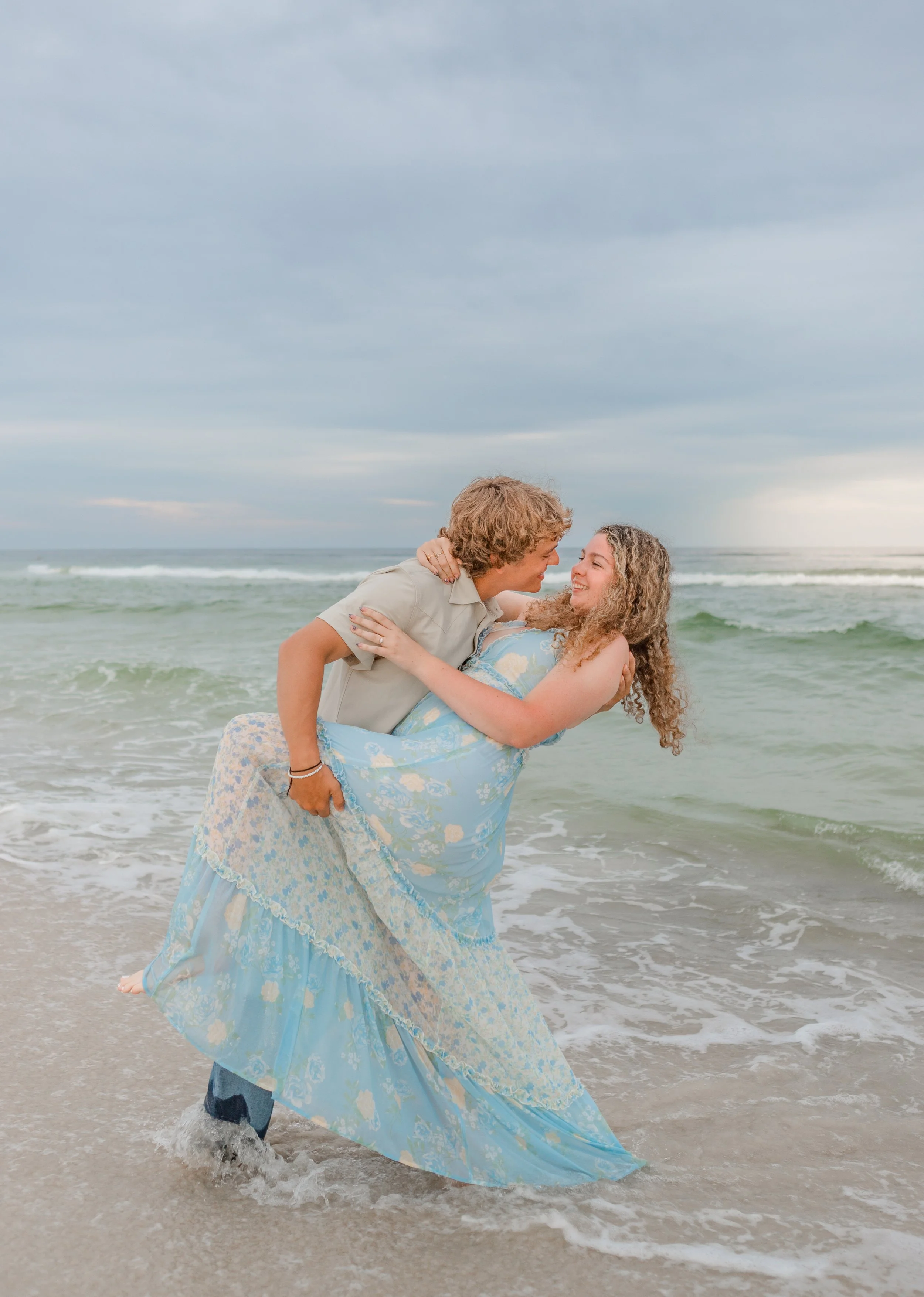 Young couple enjoying the sunset in Orange Beach, Alabama on the Gulf Coast. Man is dipping the young lady in the water for a dance. 
