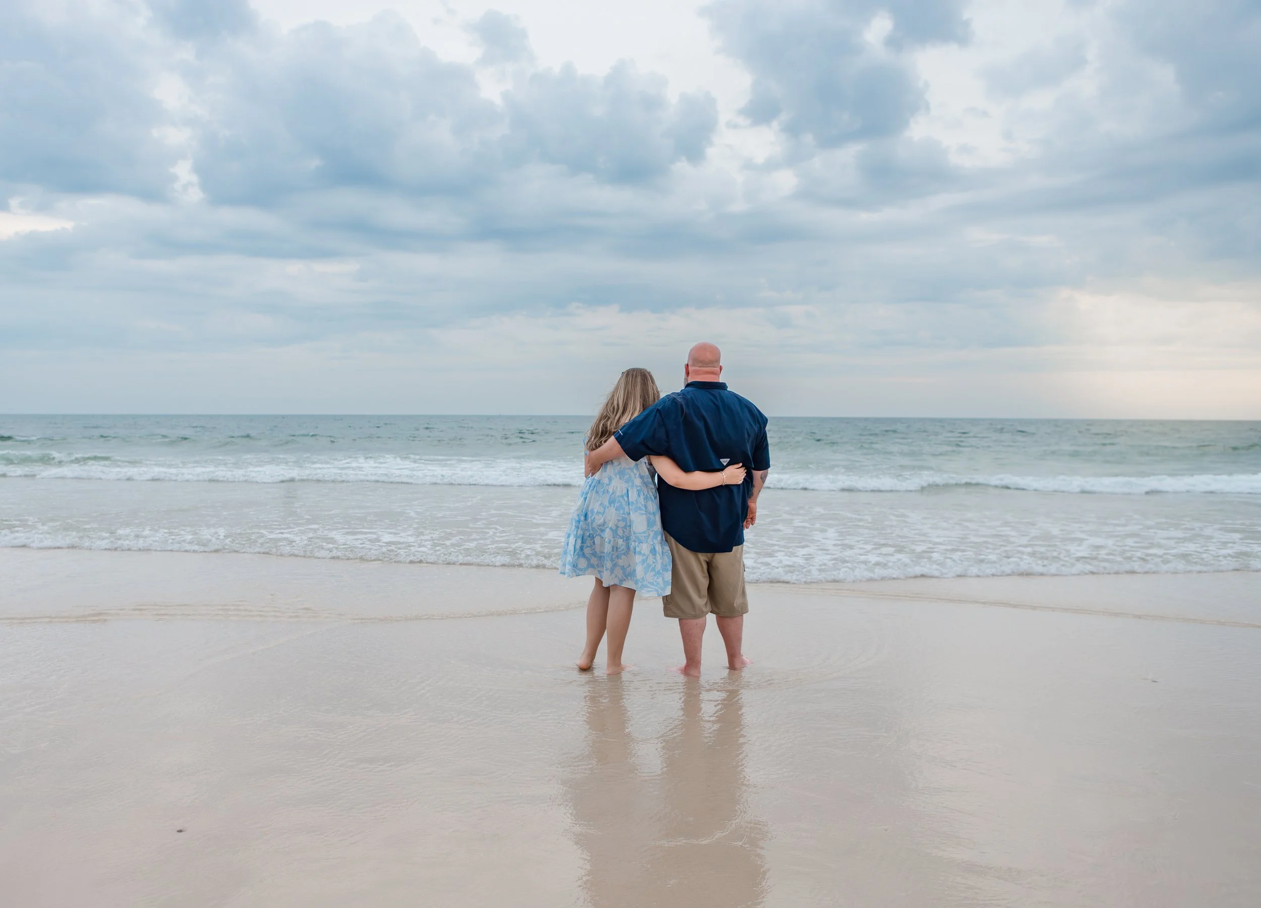 Daughter and dad looking out into the water at sunset in Orange Beach, Alabama 